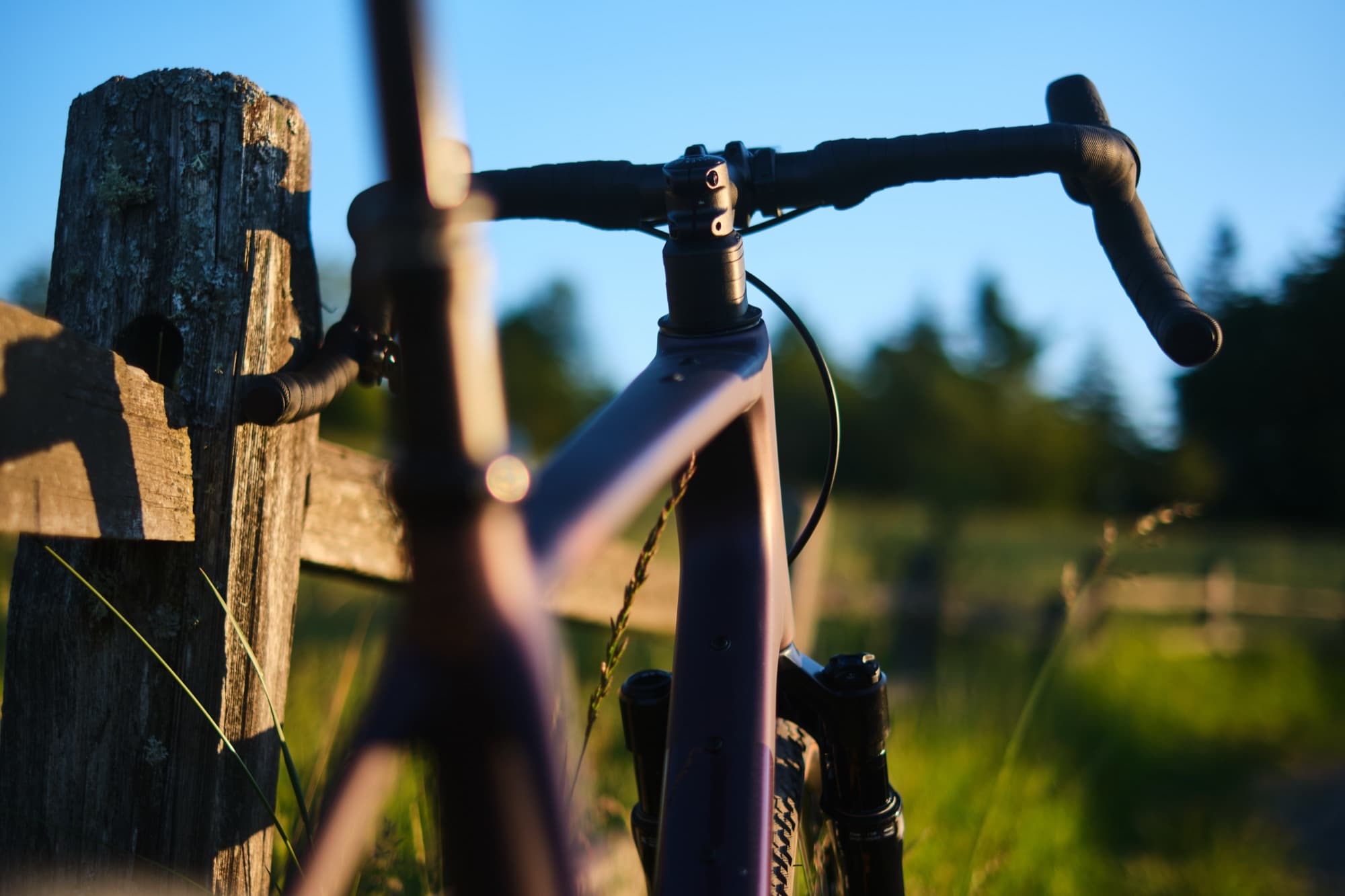 Handlebar and headtube silhouetted against a fence post