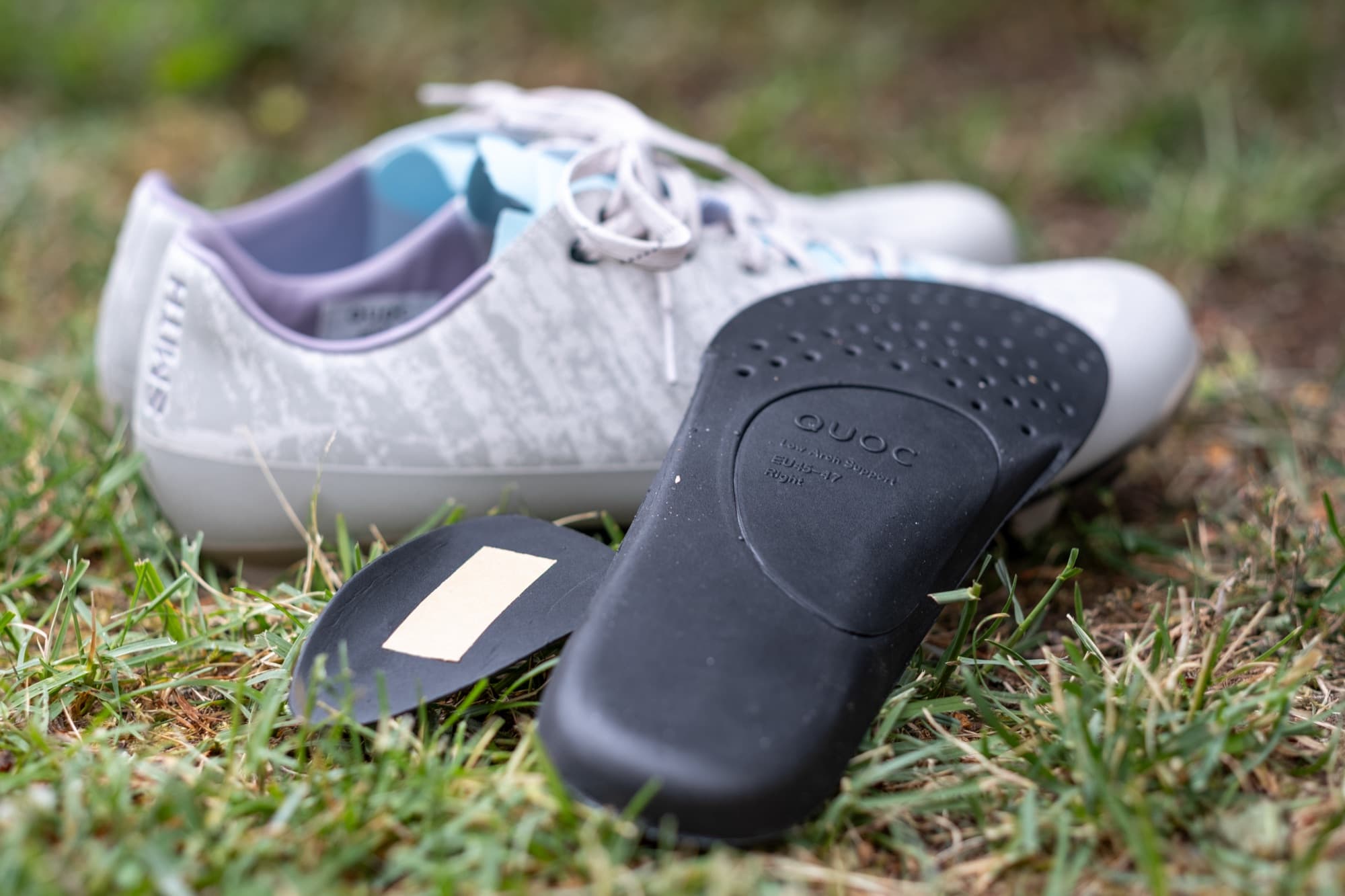 A Quoc arch support insert with its adhesive backing, beside the shoe.