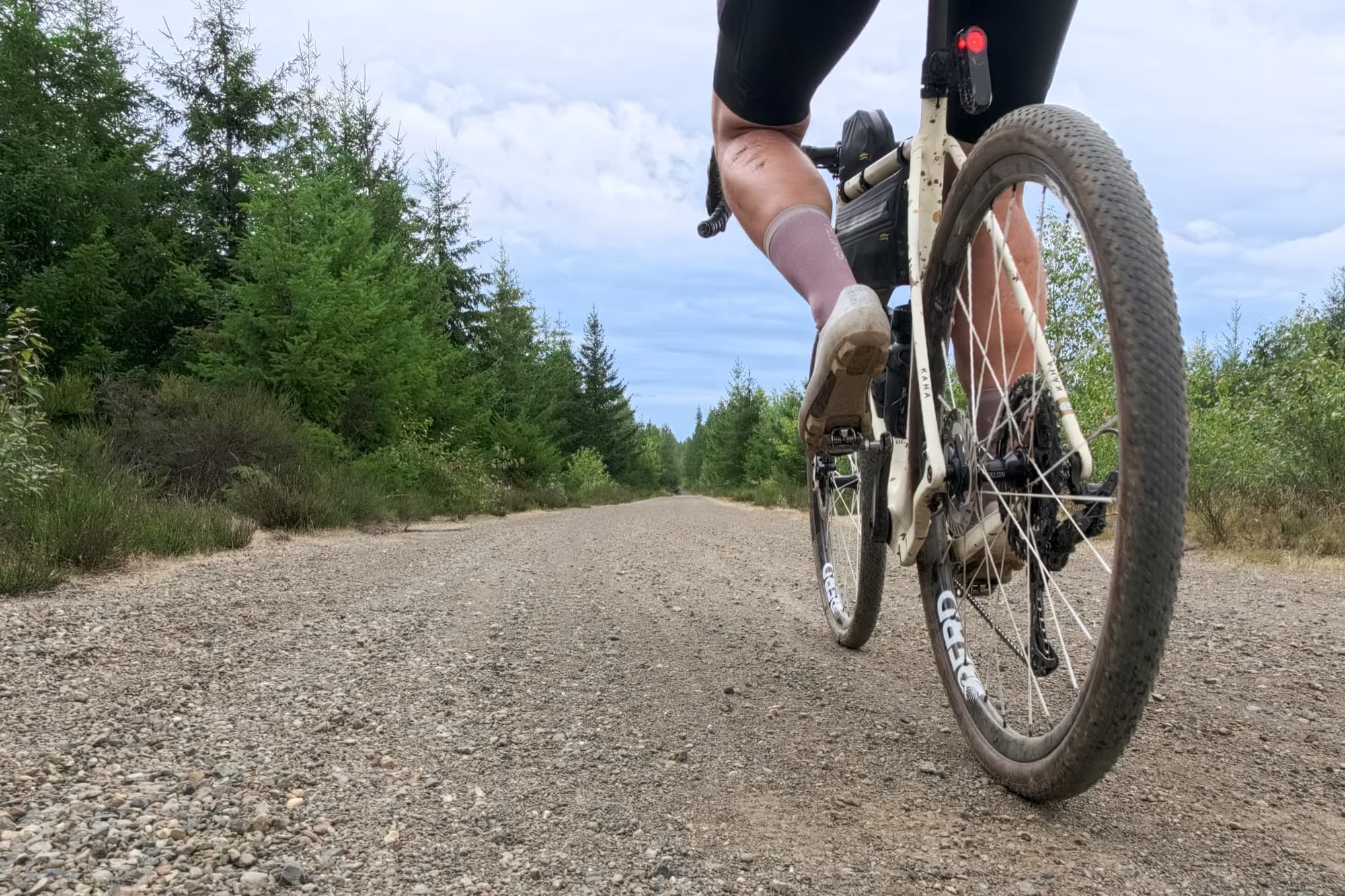 Low-angle view of Jeff riding his gravel bike down a gravel road.