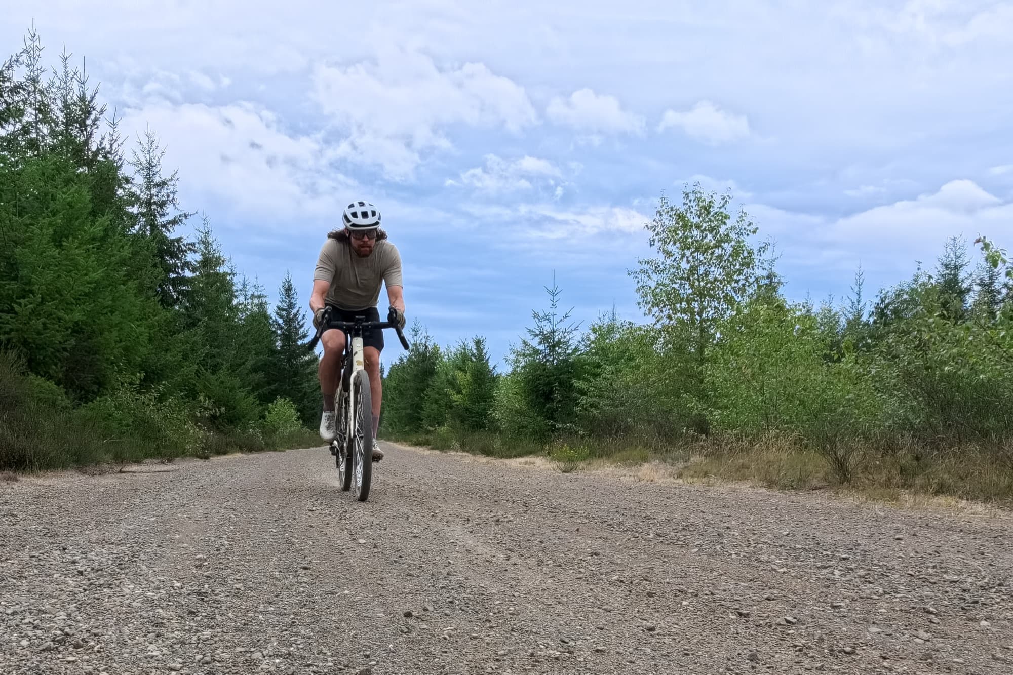Jeff rides toward the camera on a gravel forest service road.
