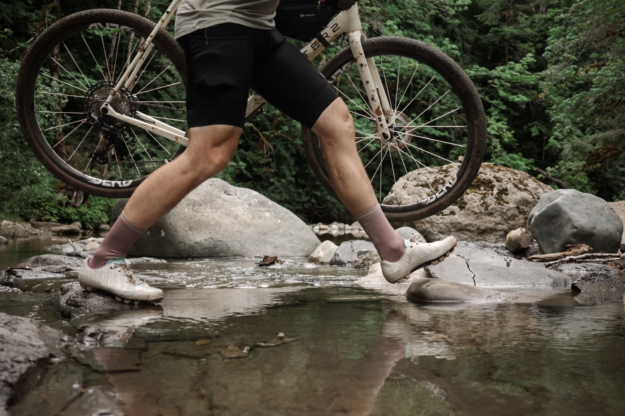 Jeff carries his bike across a rocky creek crossing in the Gran Tourer XC Lace.