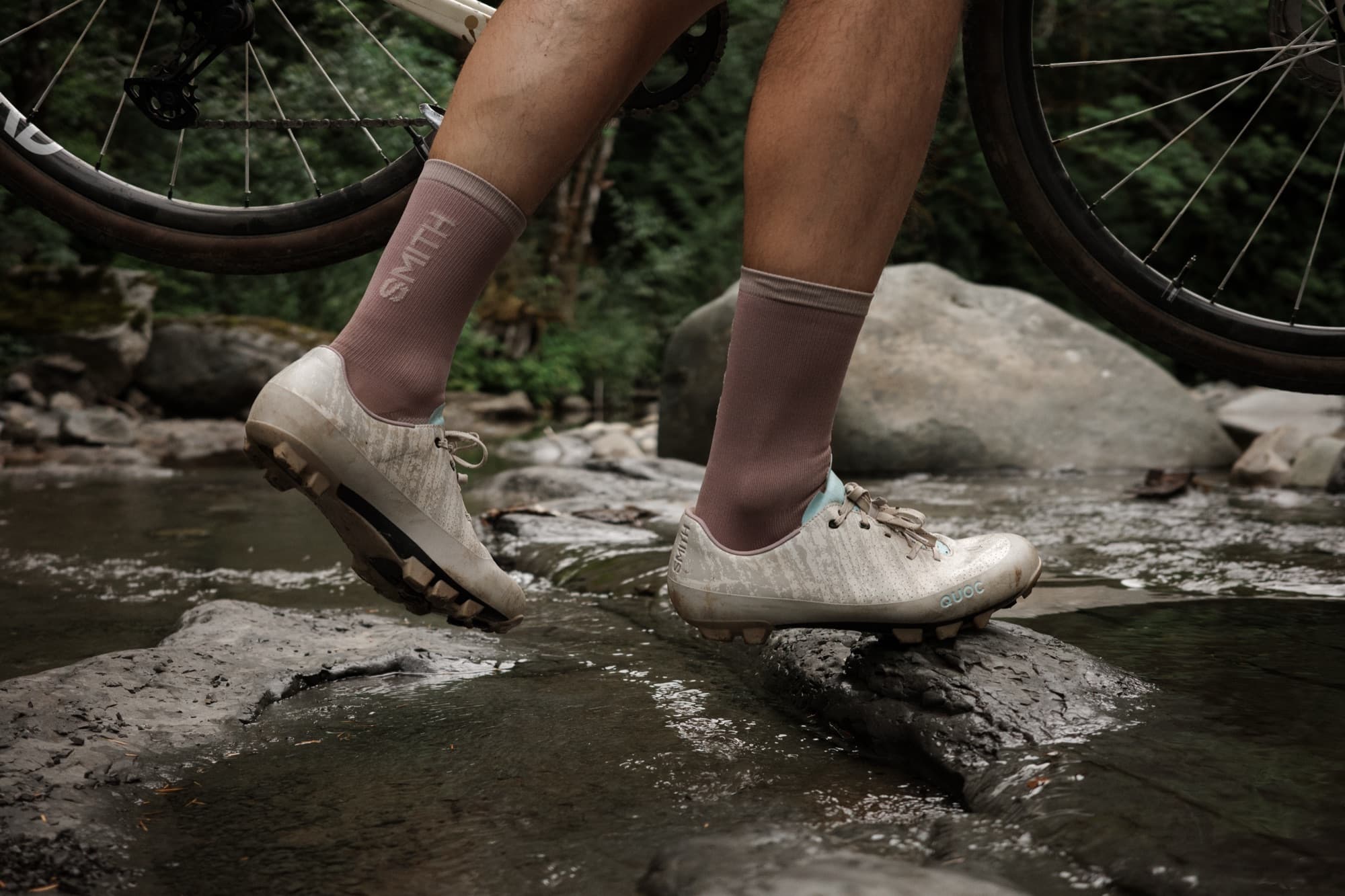 Rock-hopping across the river in the Gran Tourer XC Lace, bike in hand.
