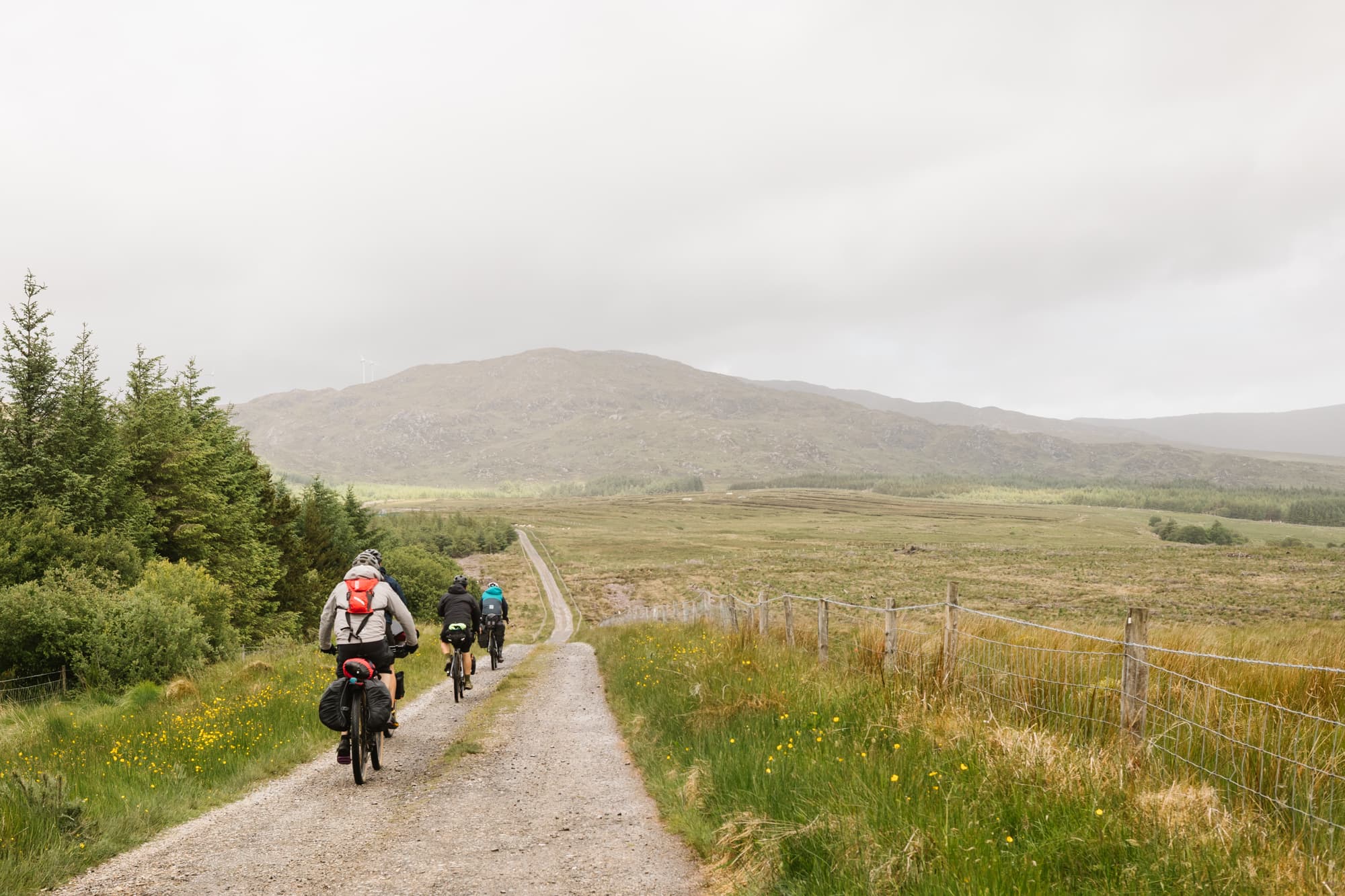 Riders roll down a quiet gravel boreen through misty Donegal moorland