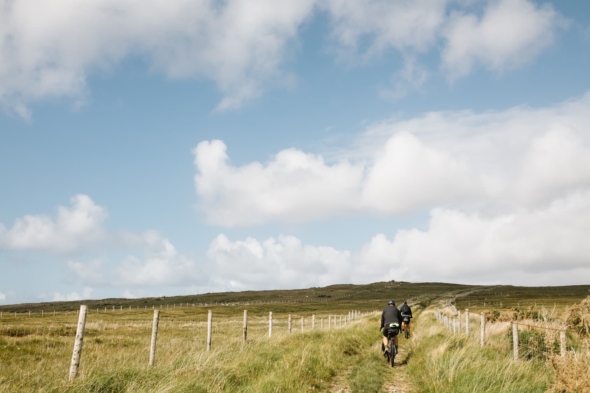 A lone rider follows a fenced farm track under a big Atlantic sky