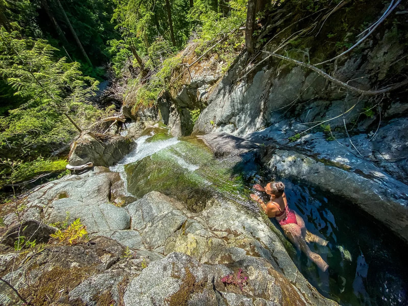 Swimming in a crystal-clear river pool below a falls