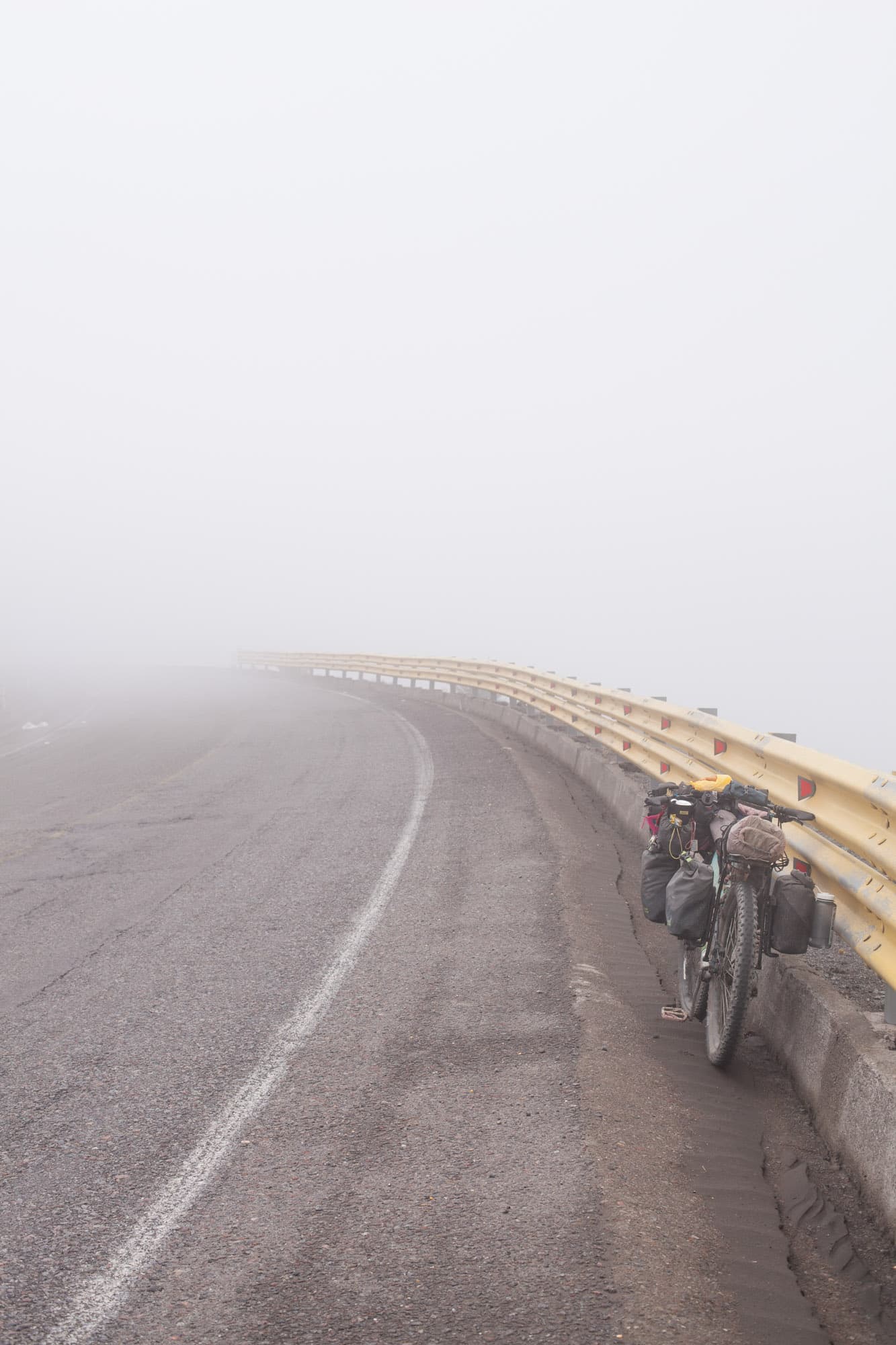 A loaded bike on a fog-shrouded mountain road.