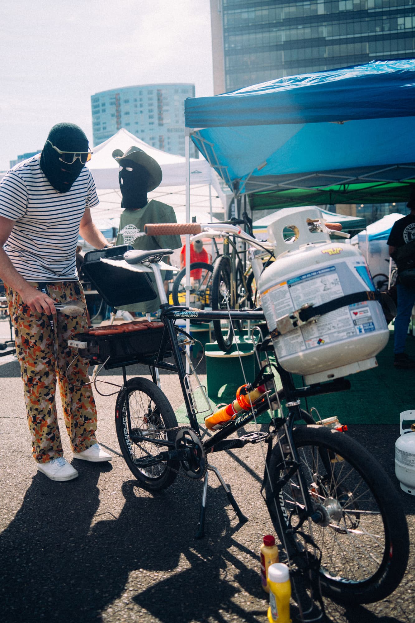 A masked man serves hot dogs.
