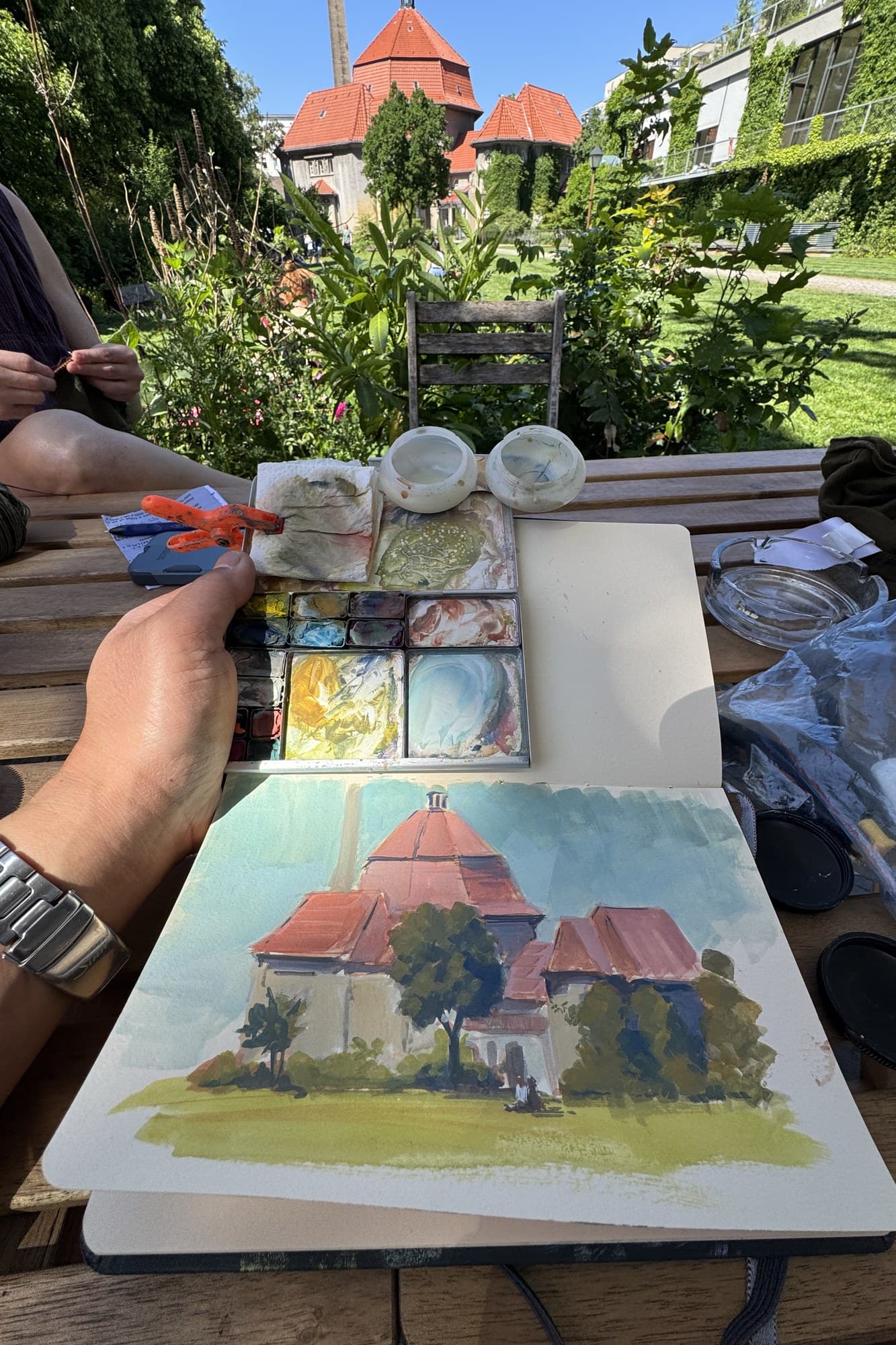 Gouache painting of a stone house on a folding table