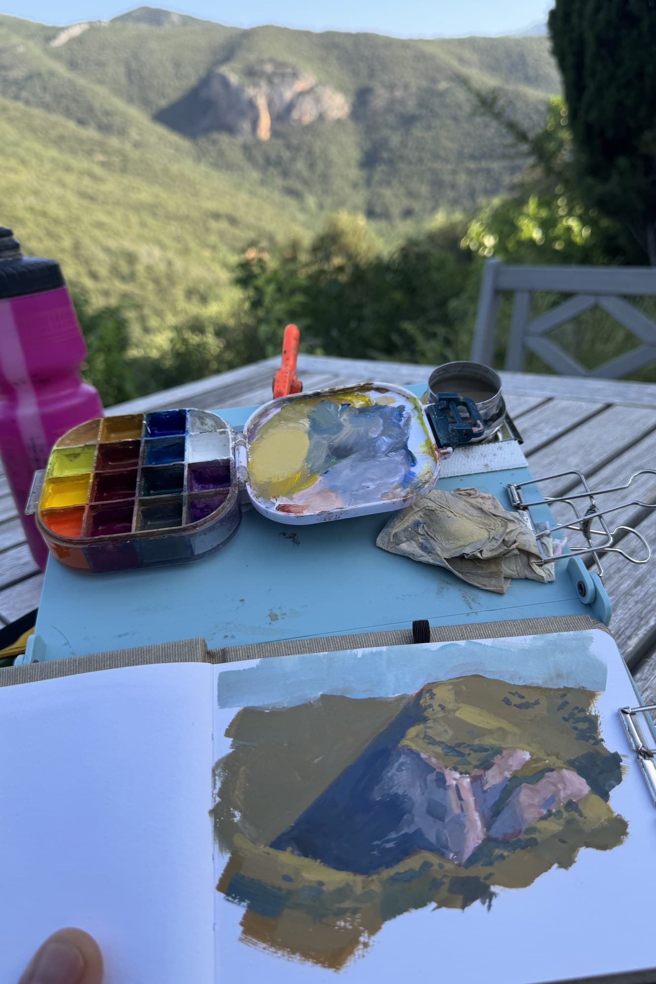 Palette and a mountain study on a picnic table