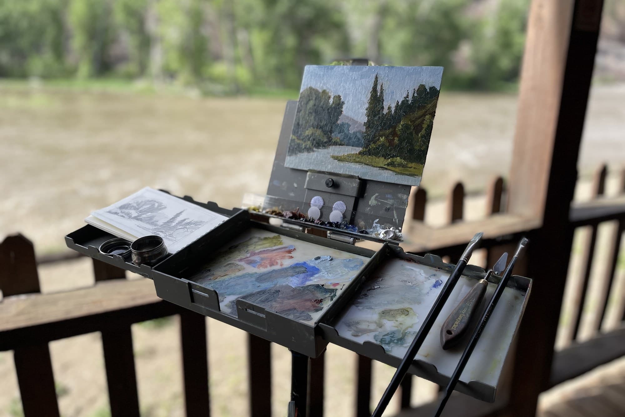 Pochade box set up on a railing over a river