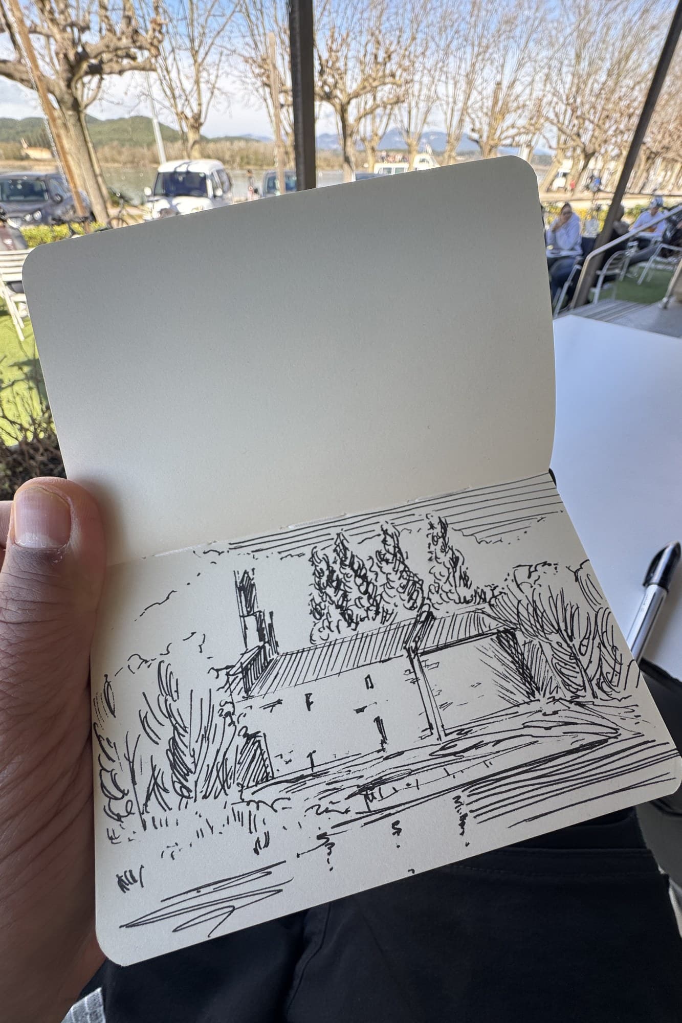 Pen sketch of a tree-lined square in a sketchbook