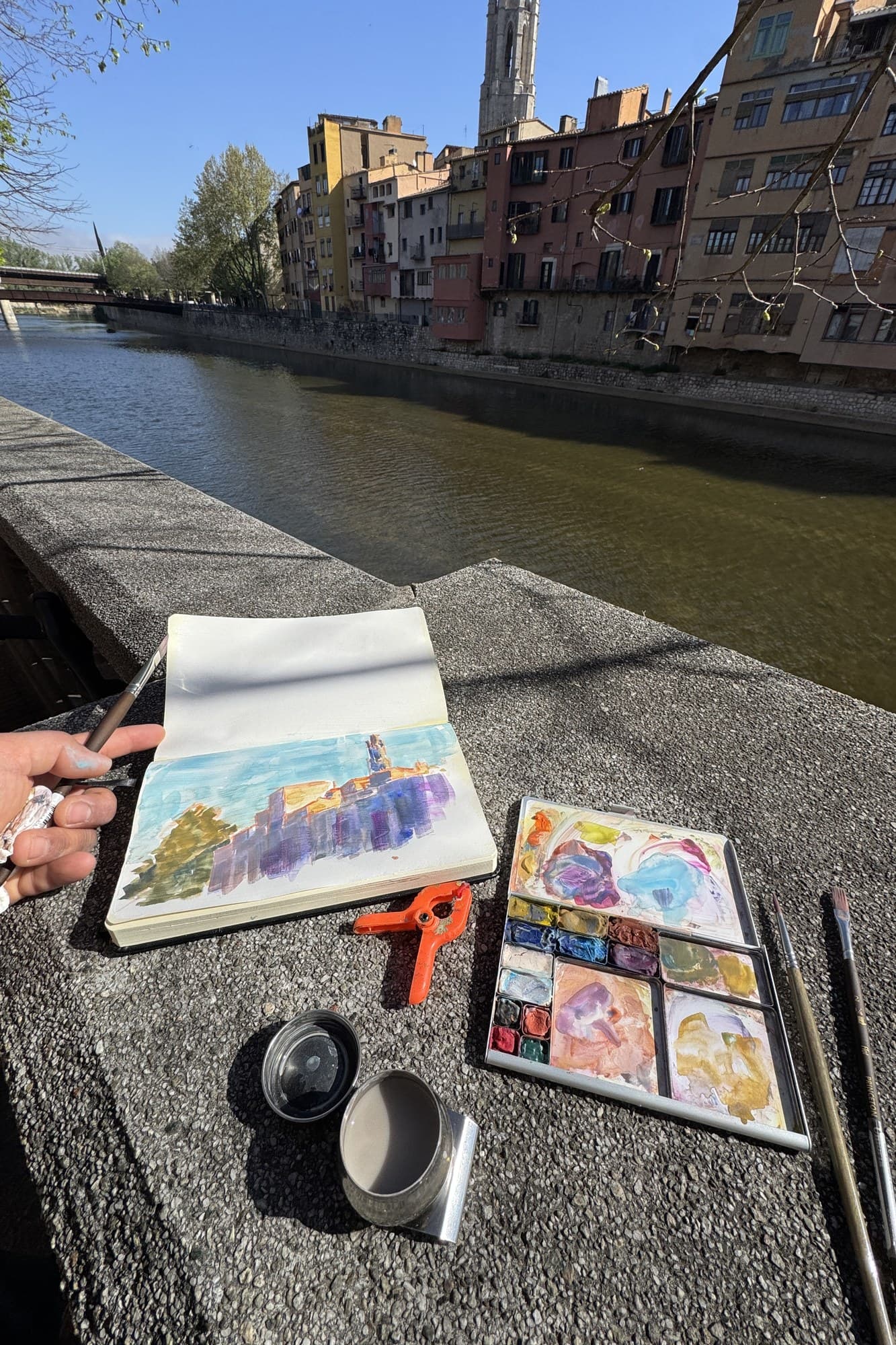 Sketchbook and palette on a stone wall by the river