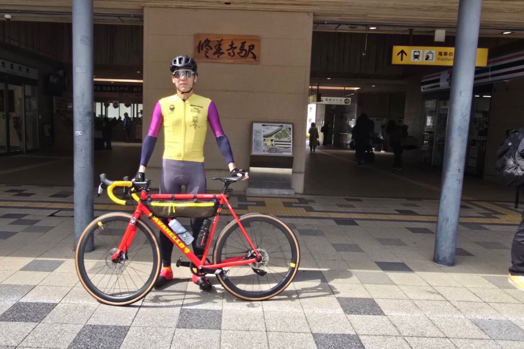 Tetsuro Ohno standing with a red gravel bike at a Japanese train station