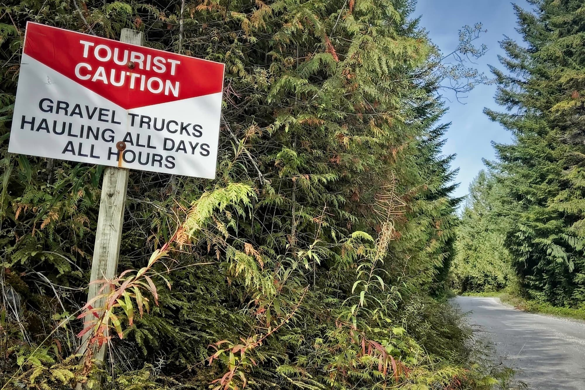Tourist caution sign warning of gravel trucks hauling all days, all hours