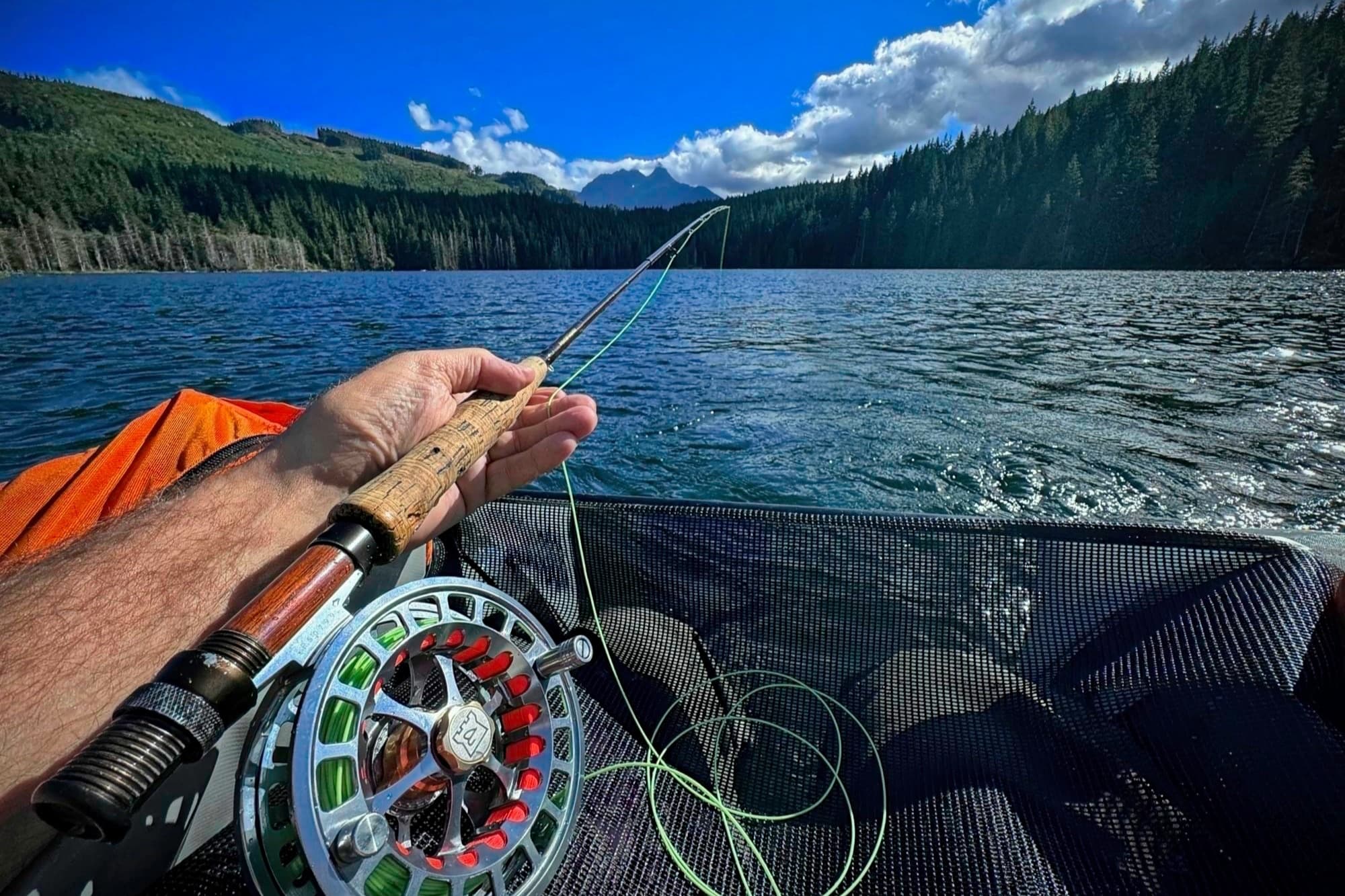 A fly rod bent over a backcountry lake from a float tube