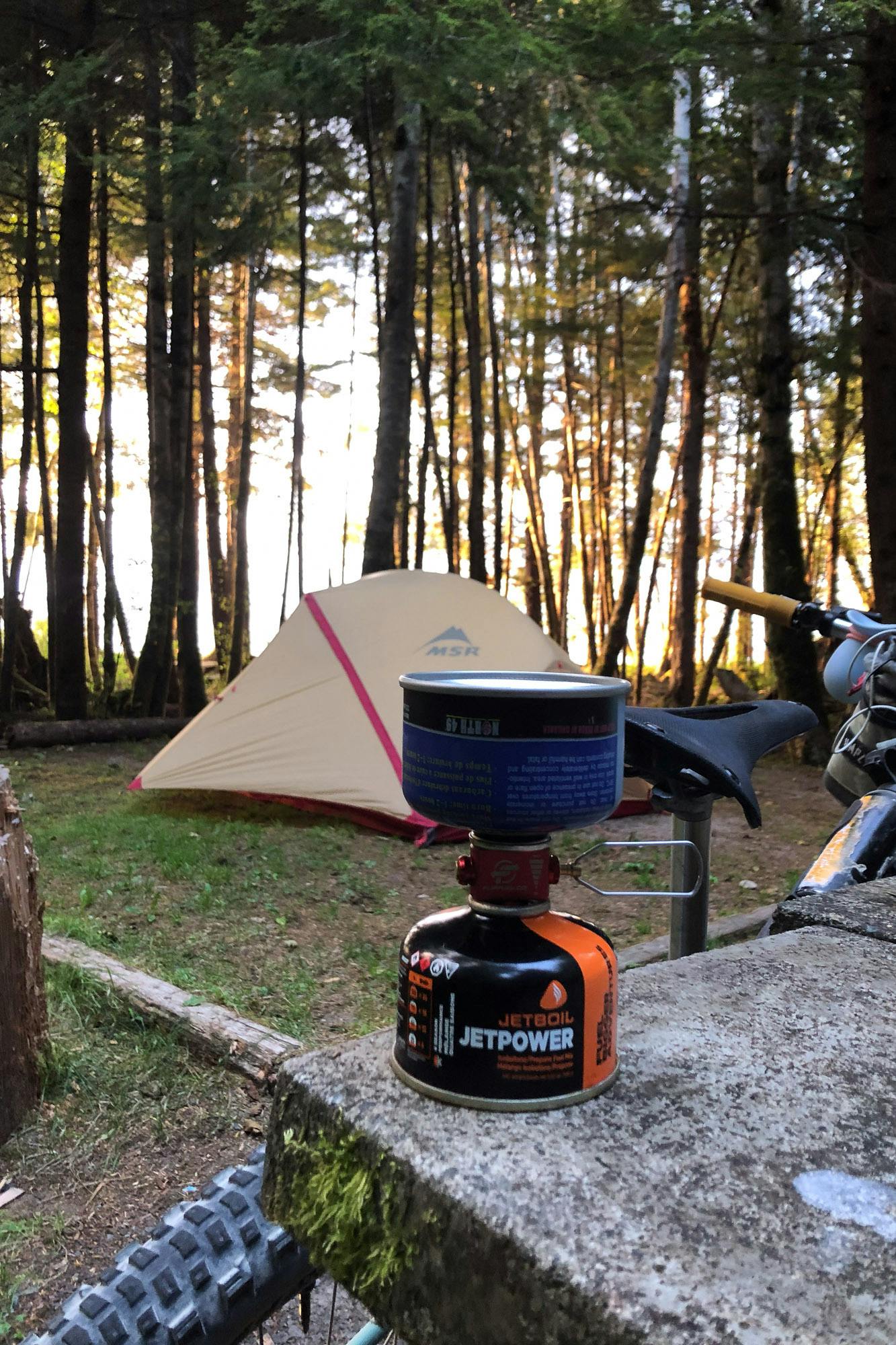 A campsite with a tent and portable stove.