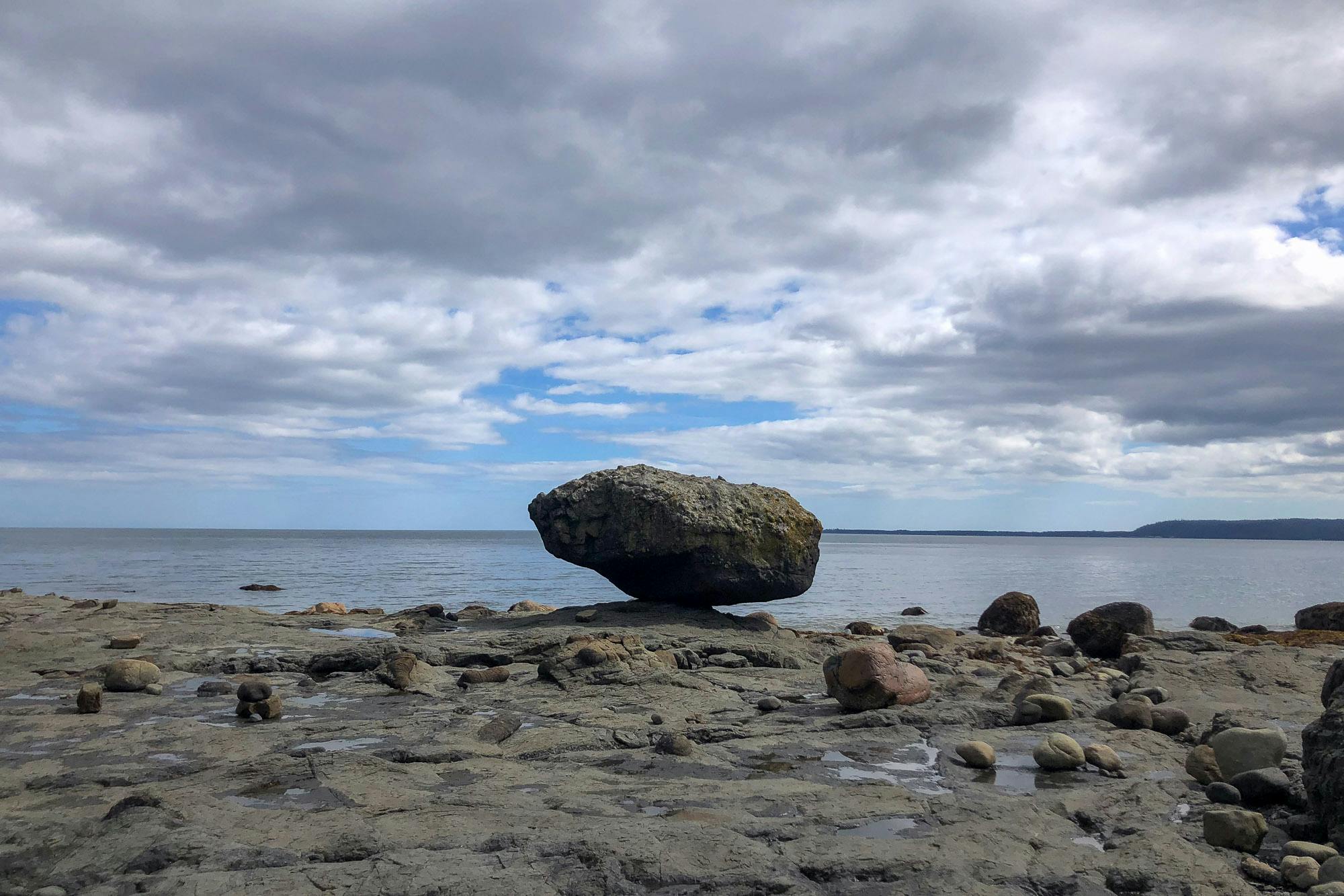 A rock balaces on the beach.