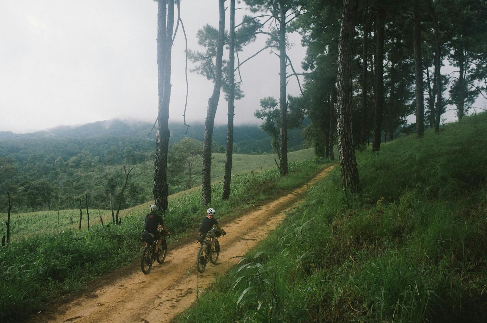 Two People Biking Up a Hill in Thailand
