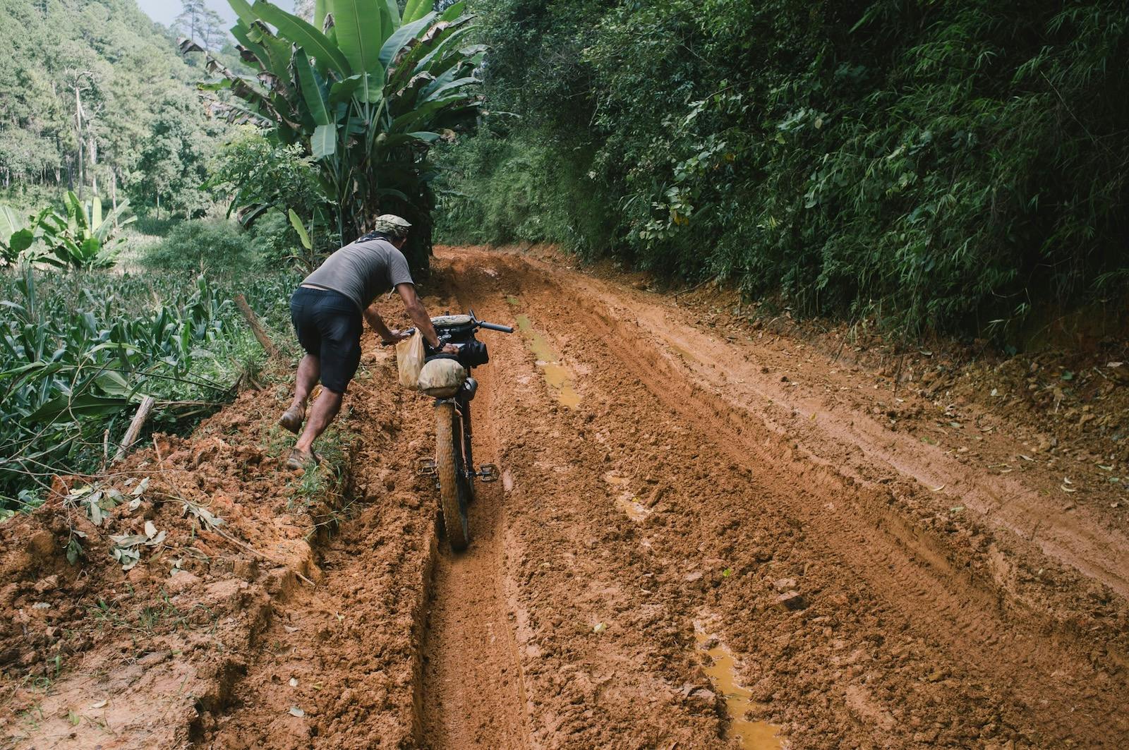 Man Pushing Bike in Mud