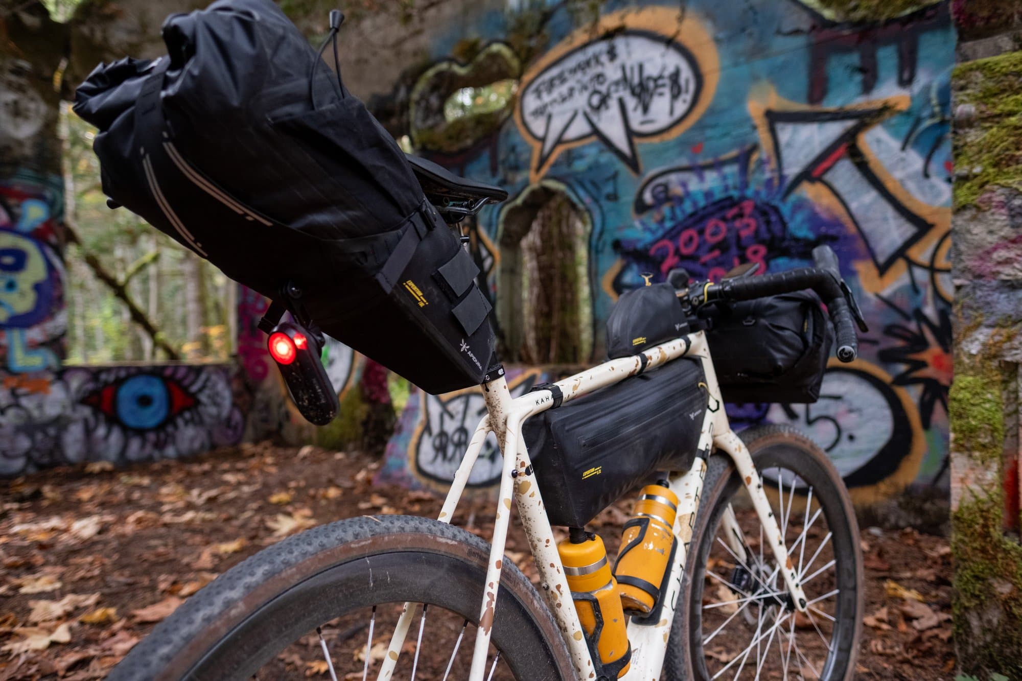 The Expedition Saddle, Frame and Handlebar Packs on the Kaha, Varia glowing, in the graffiti ruins.