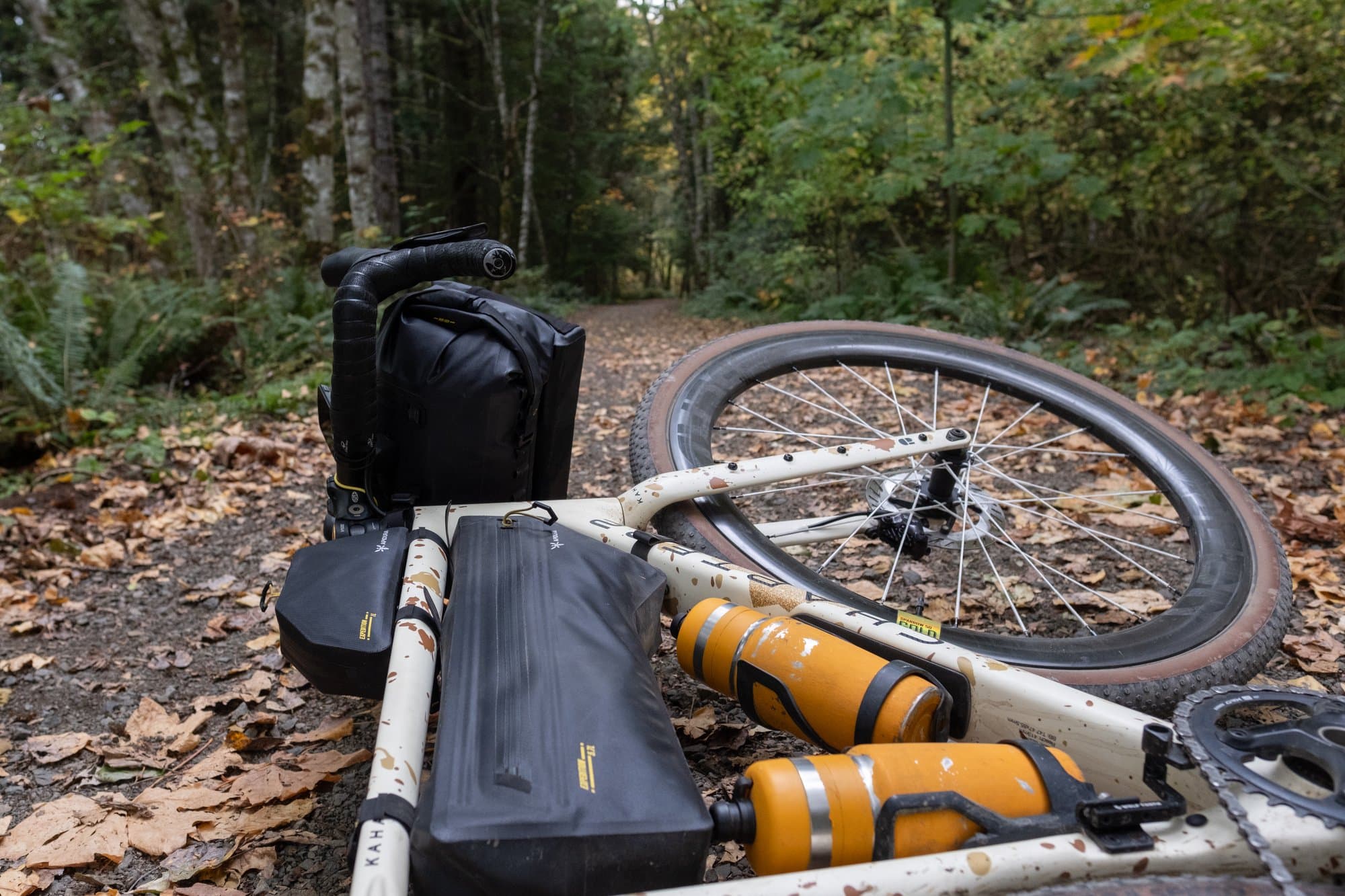 The loaded Kaha lying on a leafy trail, Frame Pack and orange bottles in the foreground.