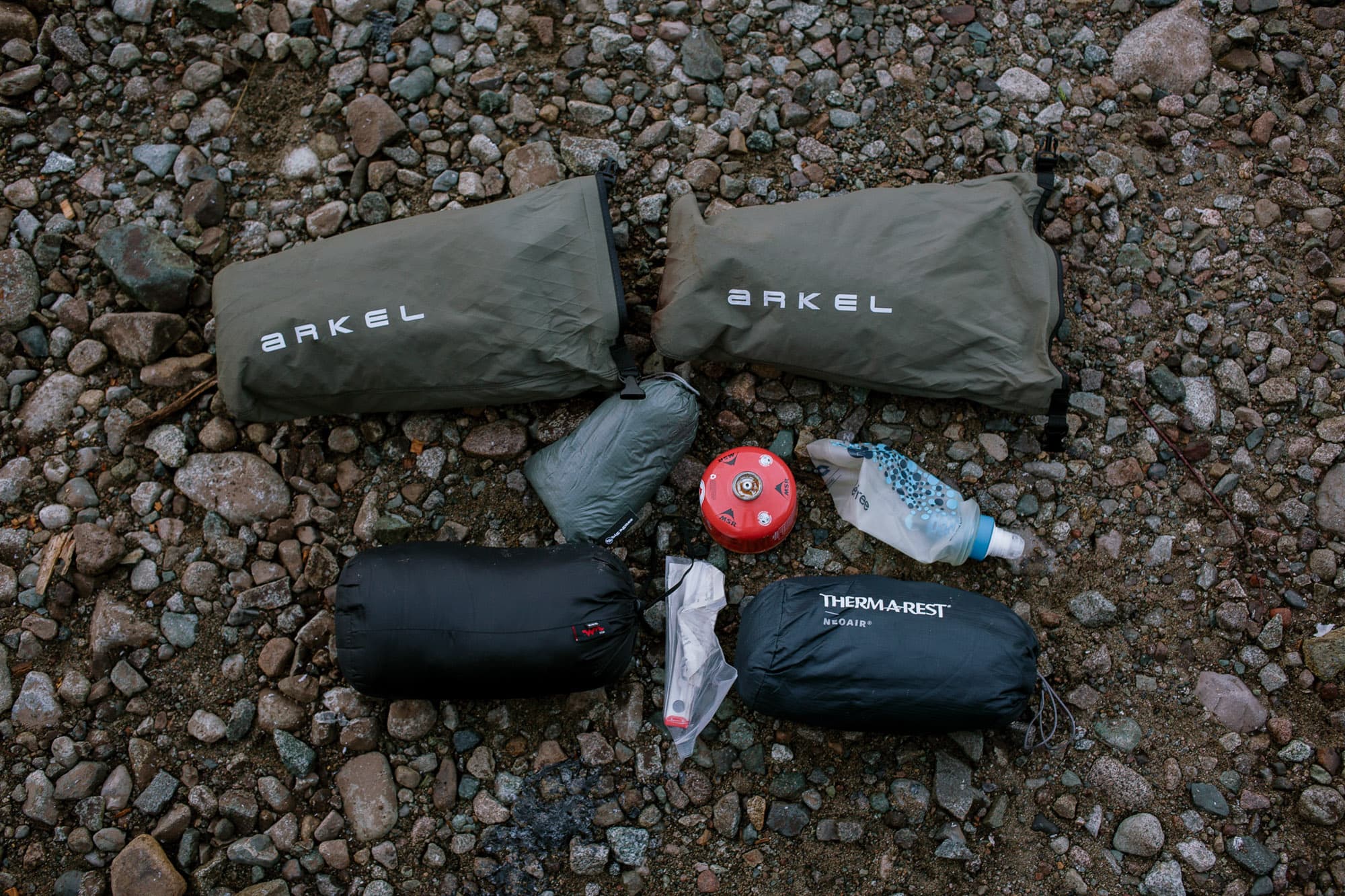 Arkel Forkpackers and Old Man Mountain FLiP cage laid out on rock.