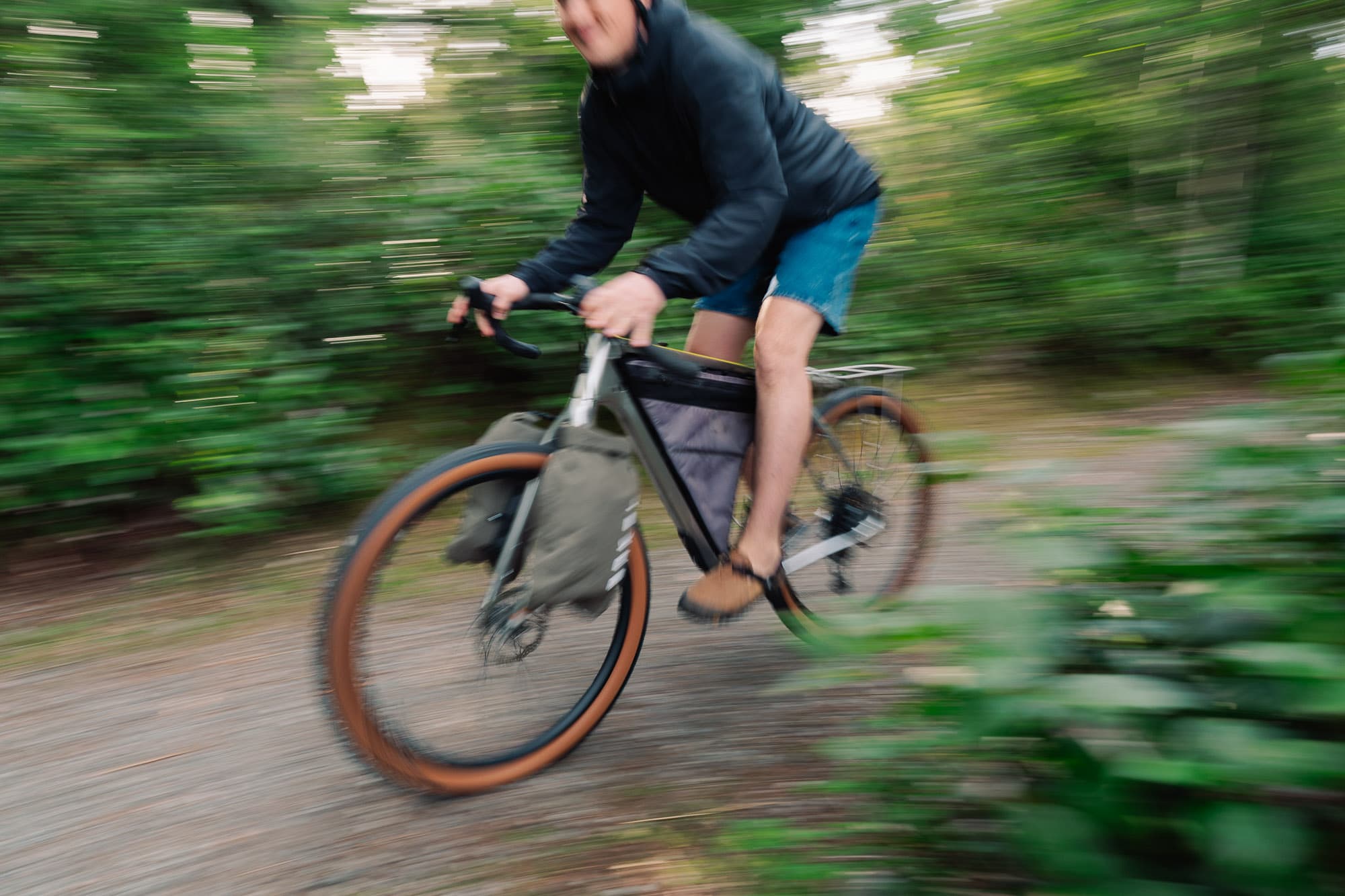 Andrew riding a loaded bike on a gravel road.