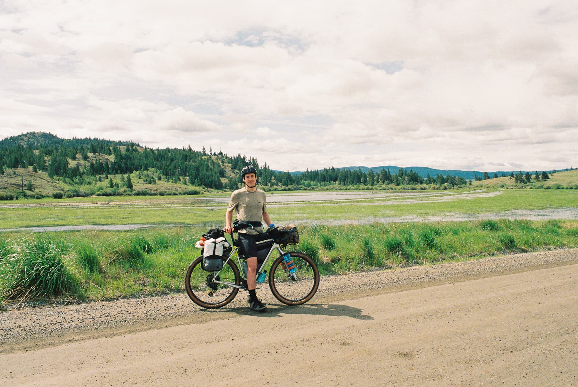 Two riders on a loaded bikepacking trip riding a dirt road in the distance.