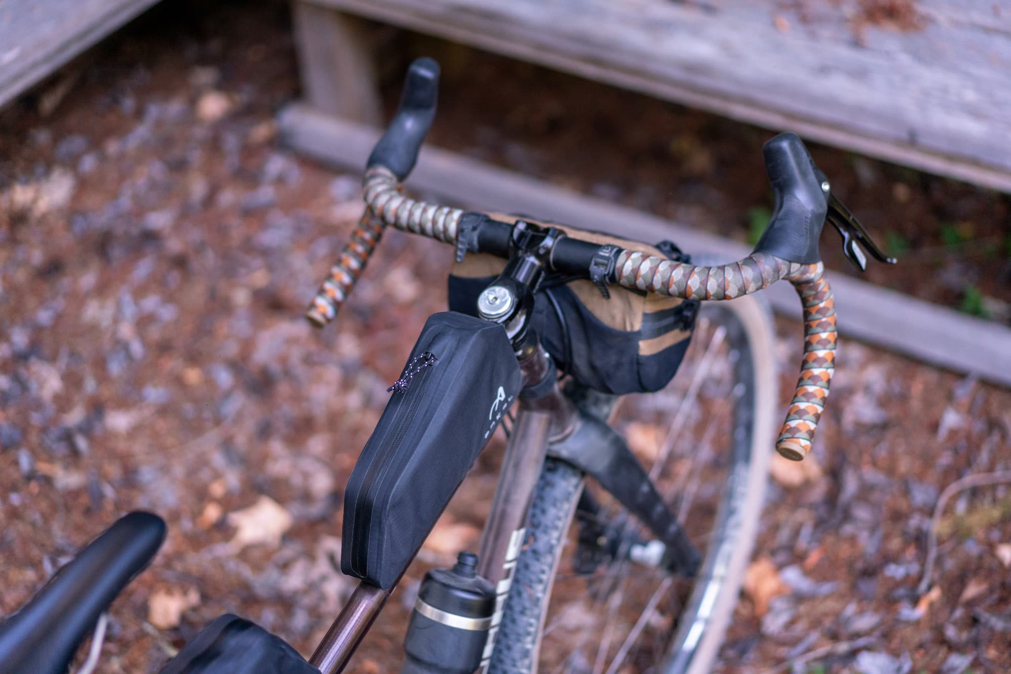 The front bag and burrito bag mounted, seen against a fallen log.
