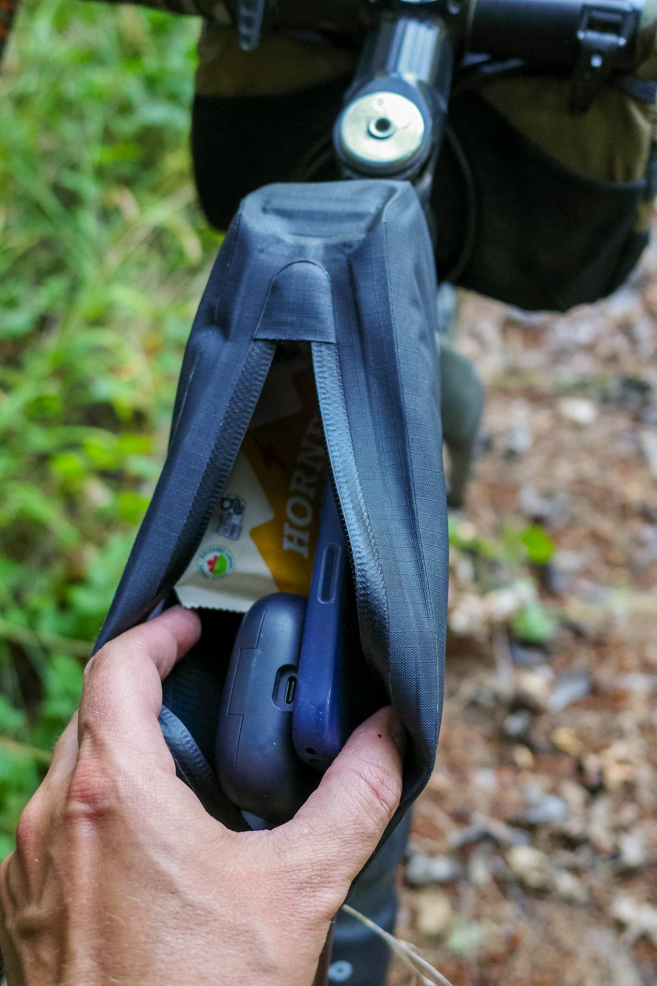 The front bag's main compartment holding a phone, earbuds, and a snack bar.