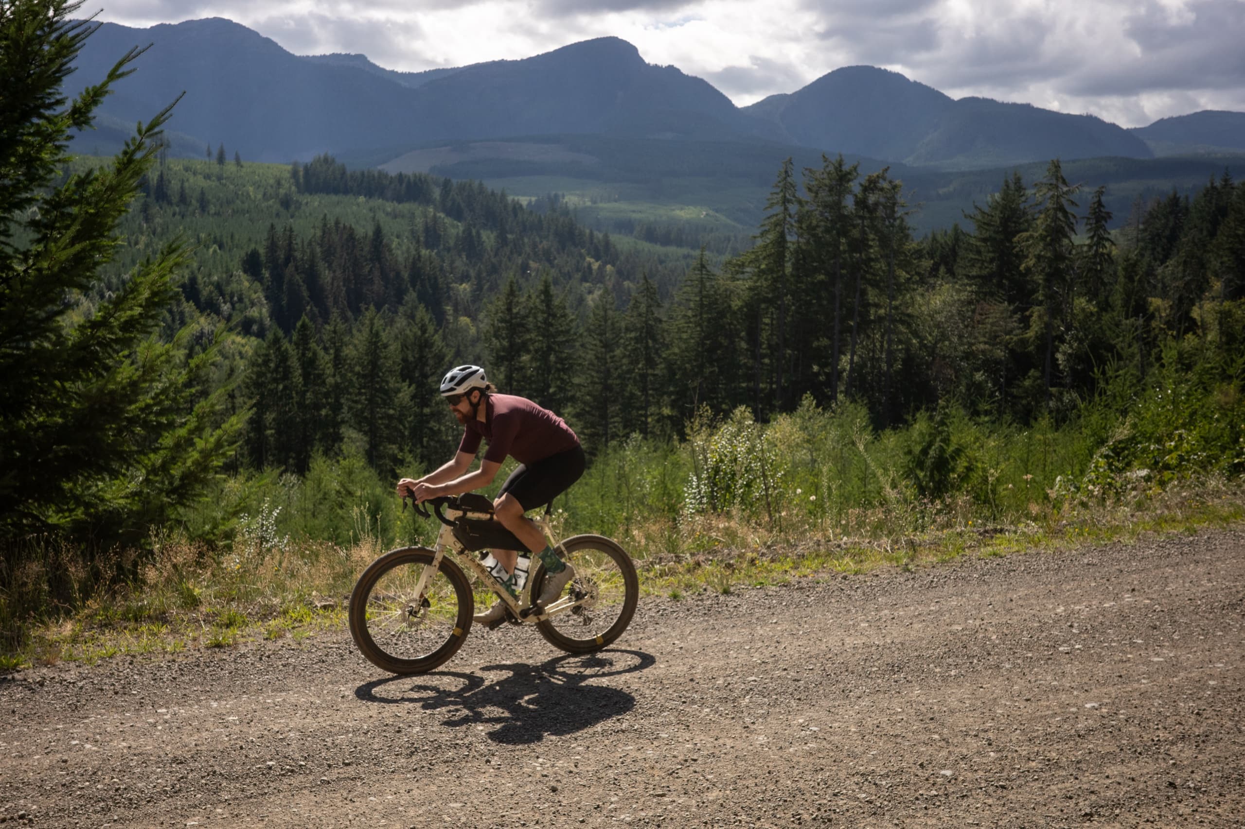 Jeff descending a gravel road with the Vancouver Island mountains behind him.