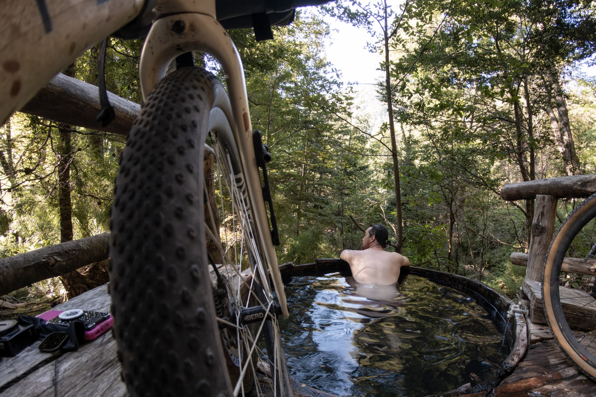 Soaking in a wooden hot tub at a forest stop with the loaded bike parked alongside.