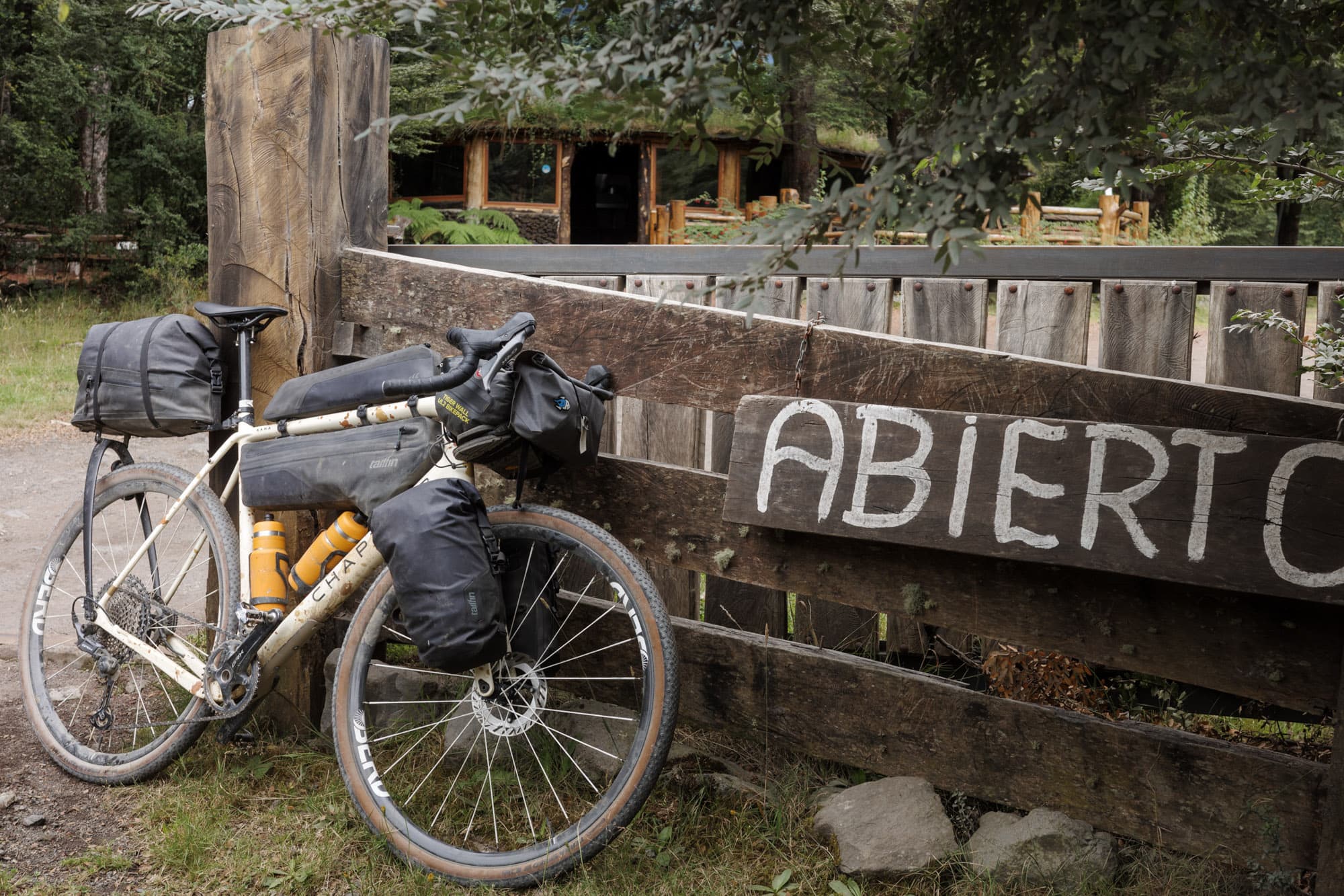 The loaded Kaha resting against an ABIERTO sign at a rural Patagonian roadside stop.