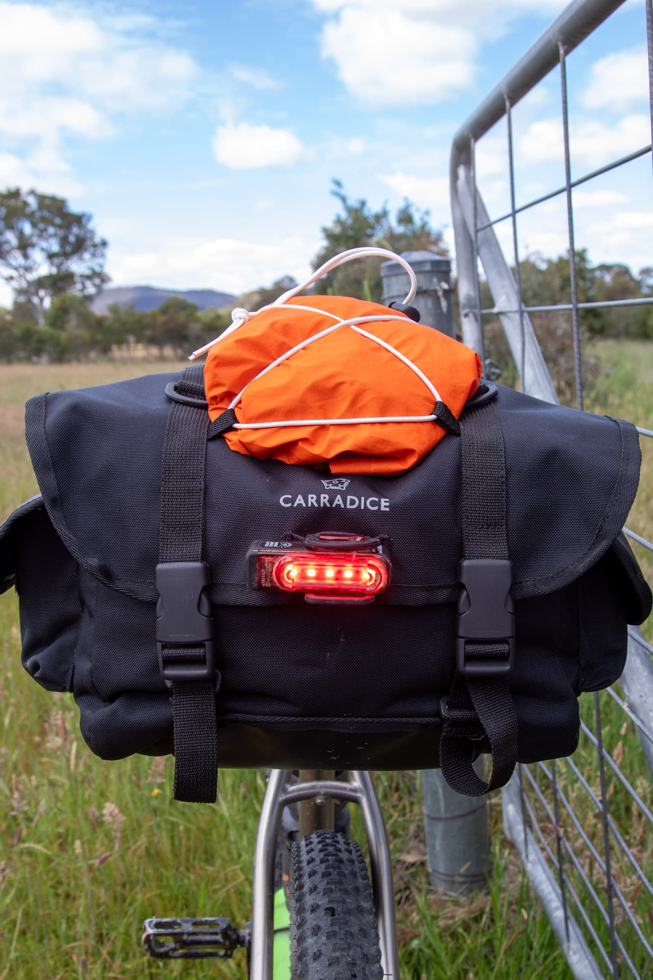 The Odyssey mounted on the rear rack with its rear light on.