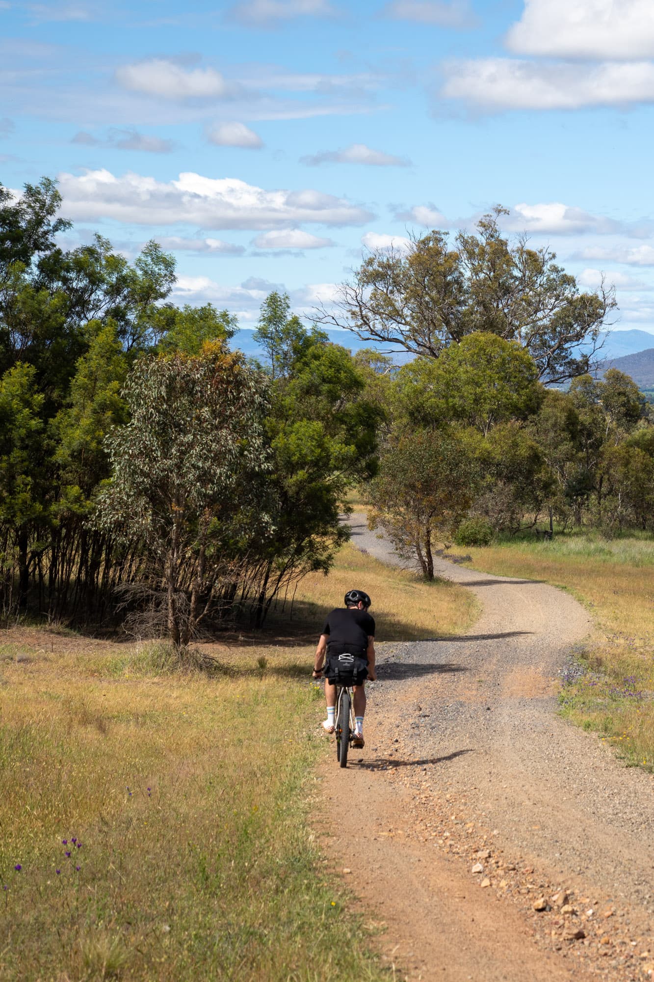 Riding away down a gravel path through the bush.