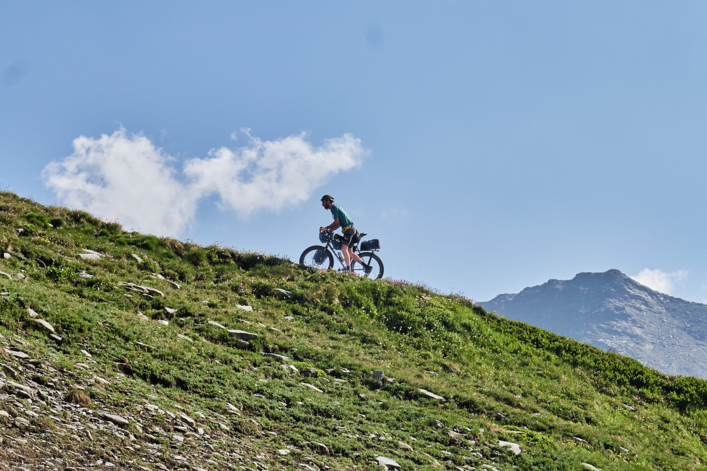 Davide riding a grassy Alpine ridge on the HiFi Session25 wheels.