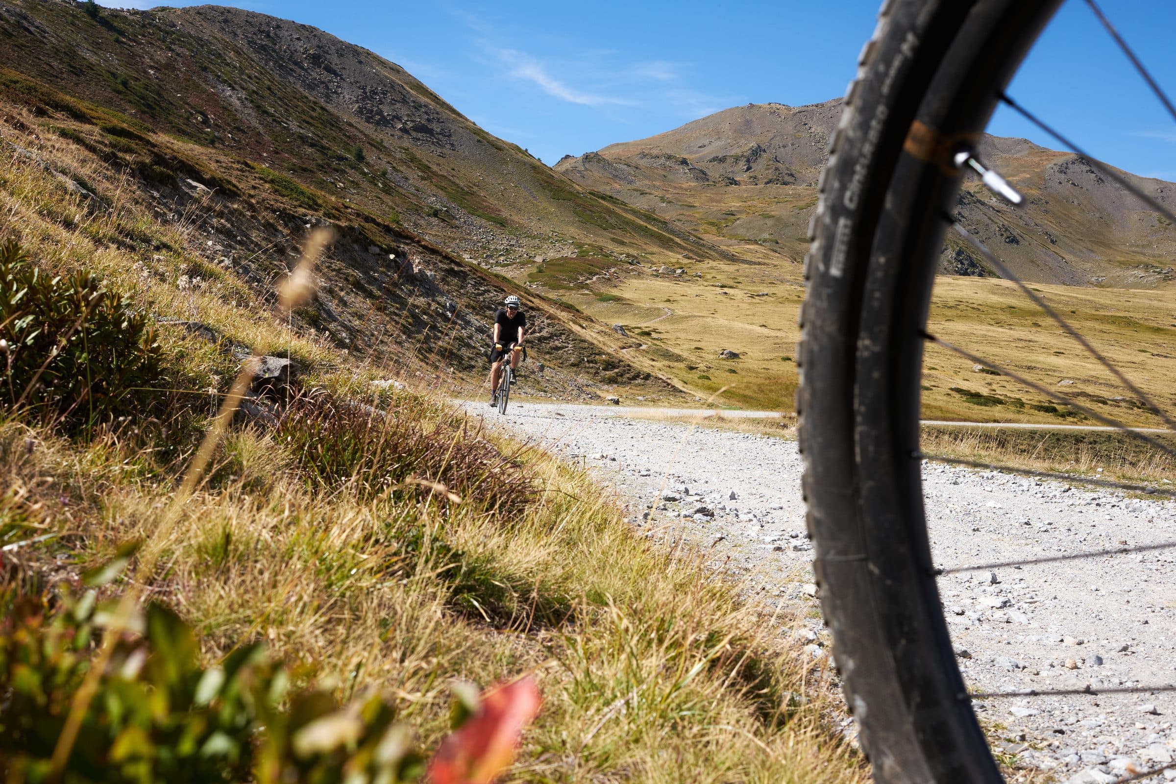 Riders on an Alpine gravel road framed by a HiFi wheel.