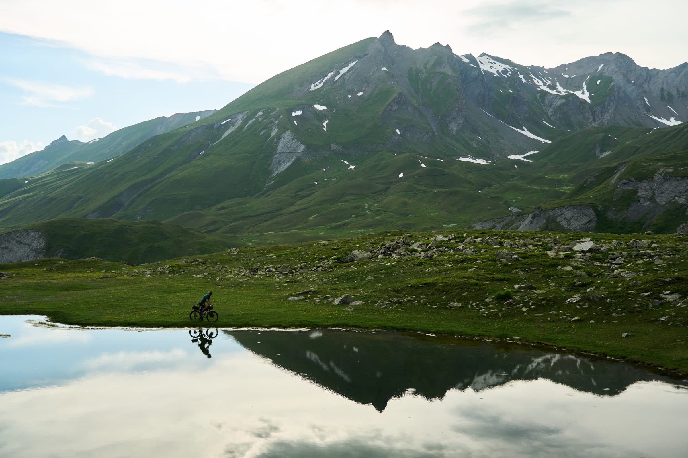 A loaded bike reflected in an Alpine lake.