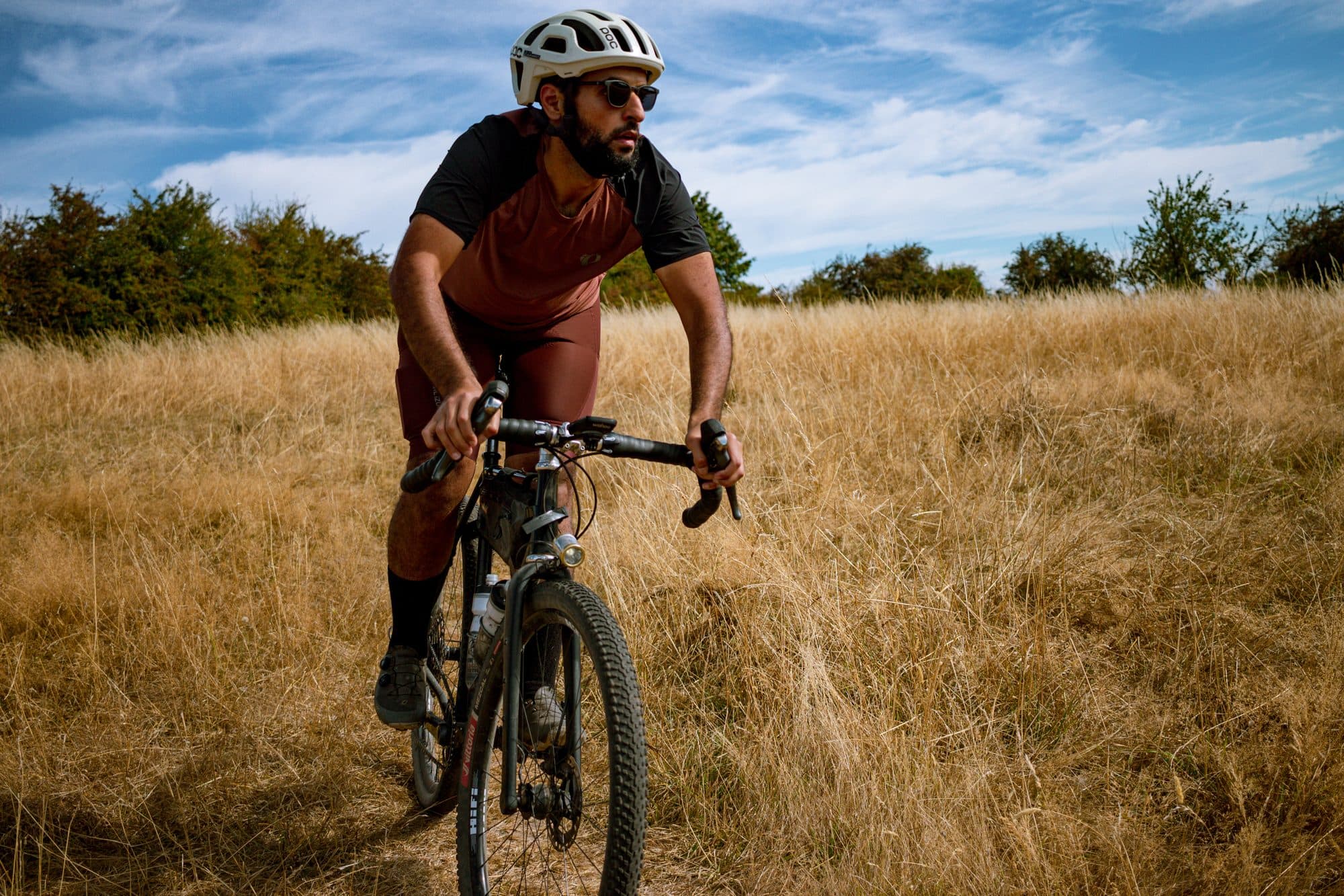Abe riding through tall golden grass in the Pearl Izumi Expedition kit.