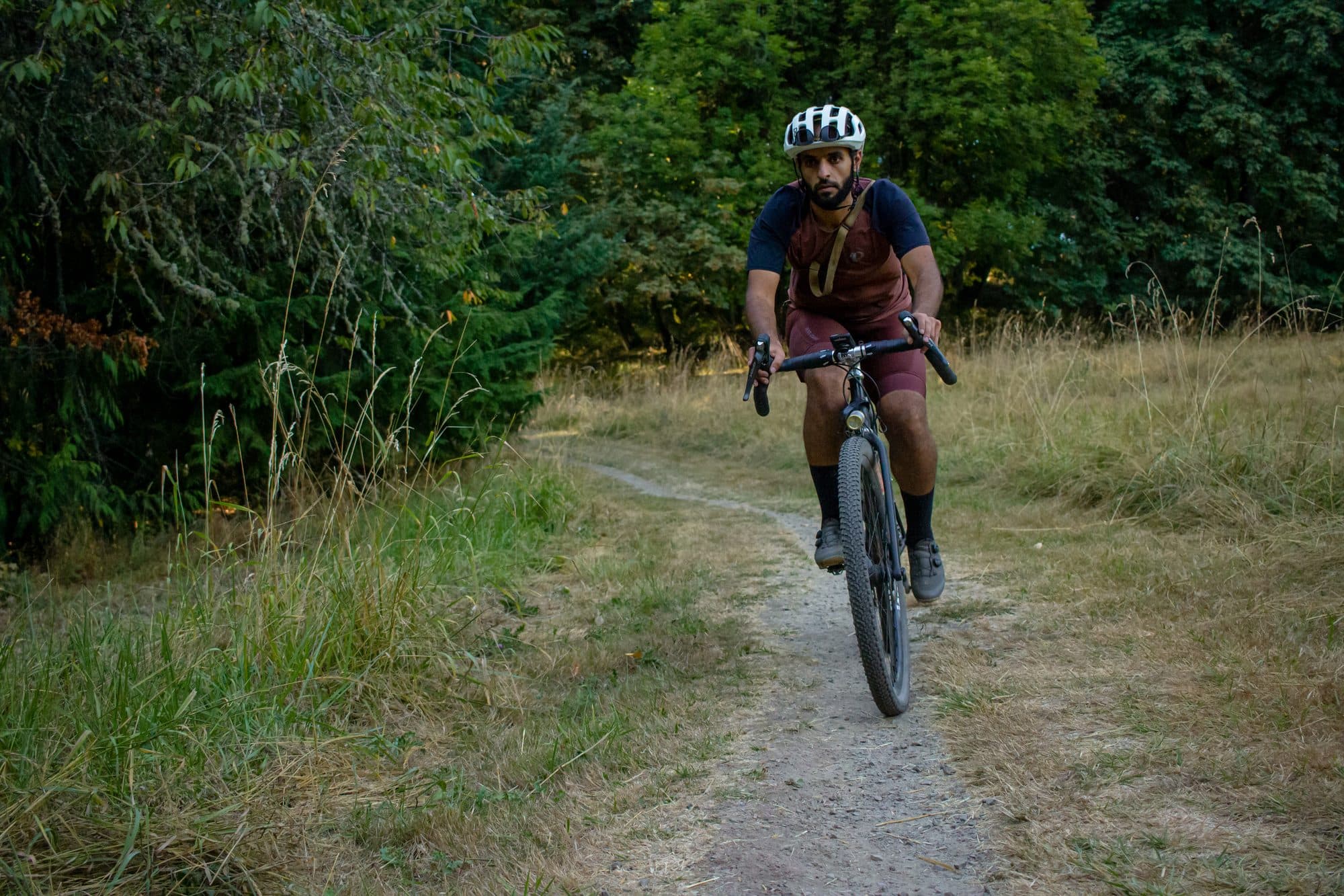 Riding toward camera on grassy doubletrack at the forest edge.