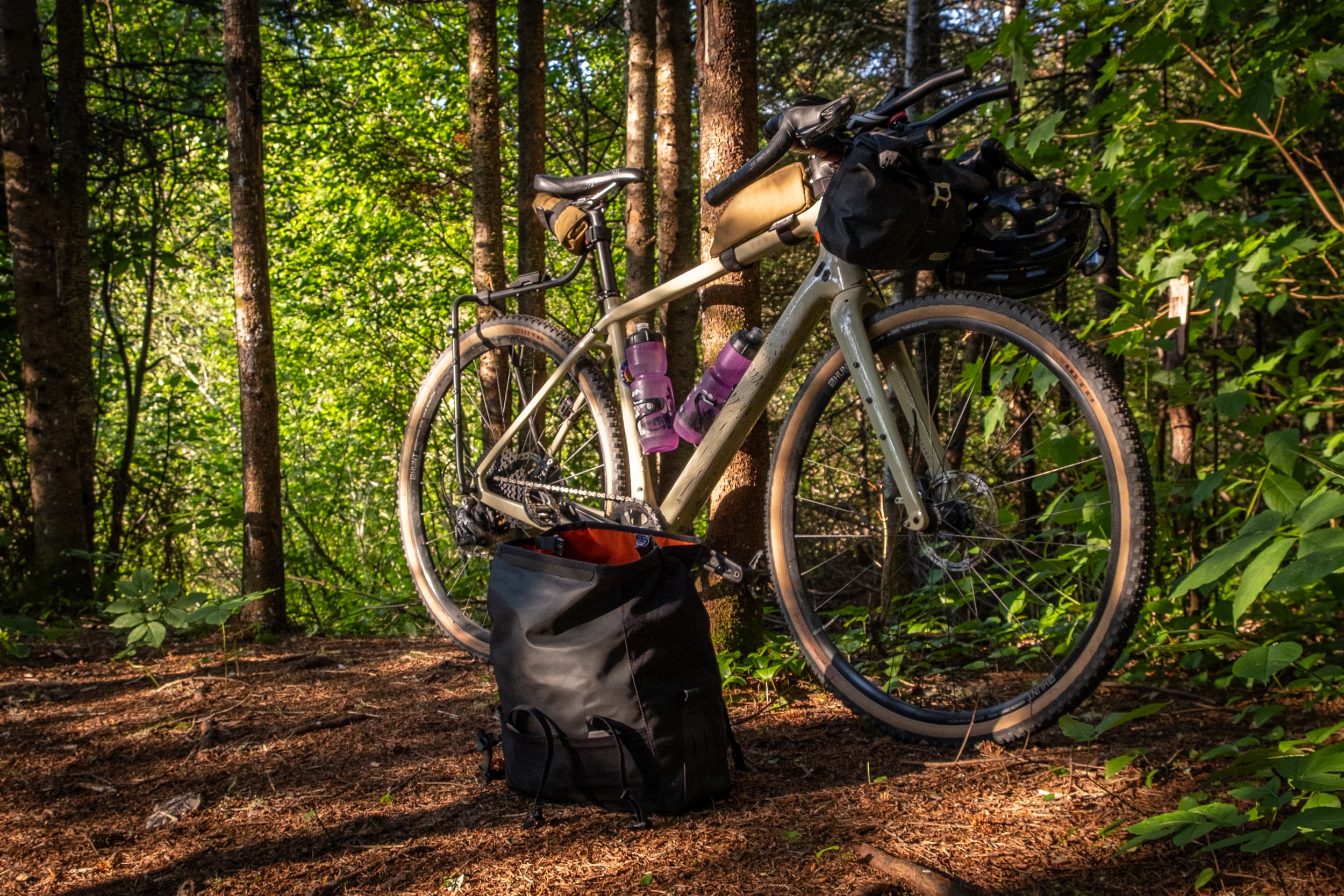 Restrap Switch Top Bag off the rack beside a loaded gravel bike in the forest.