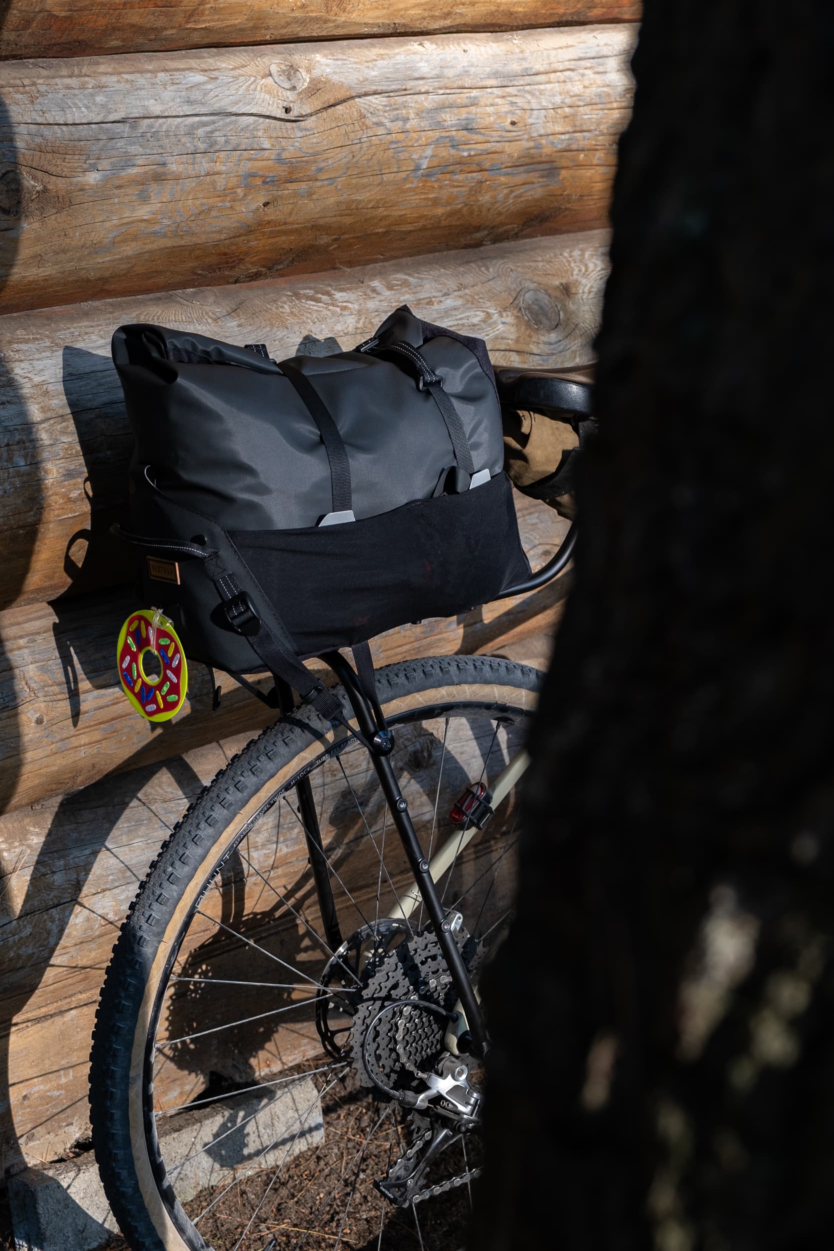 Restrap Switch Top Bag mounted on the rack, glowing in late-day light against a log cabin wall.