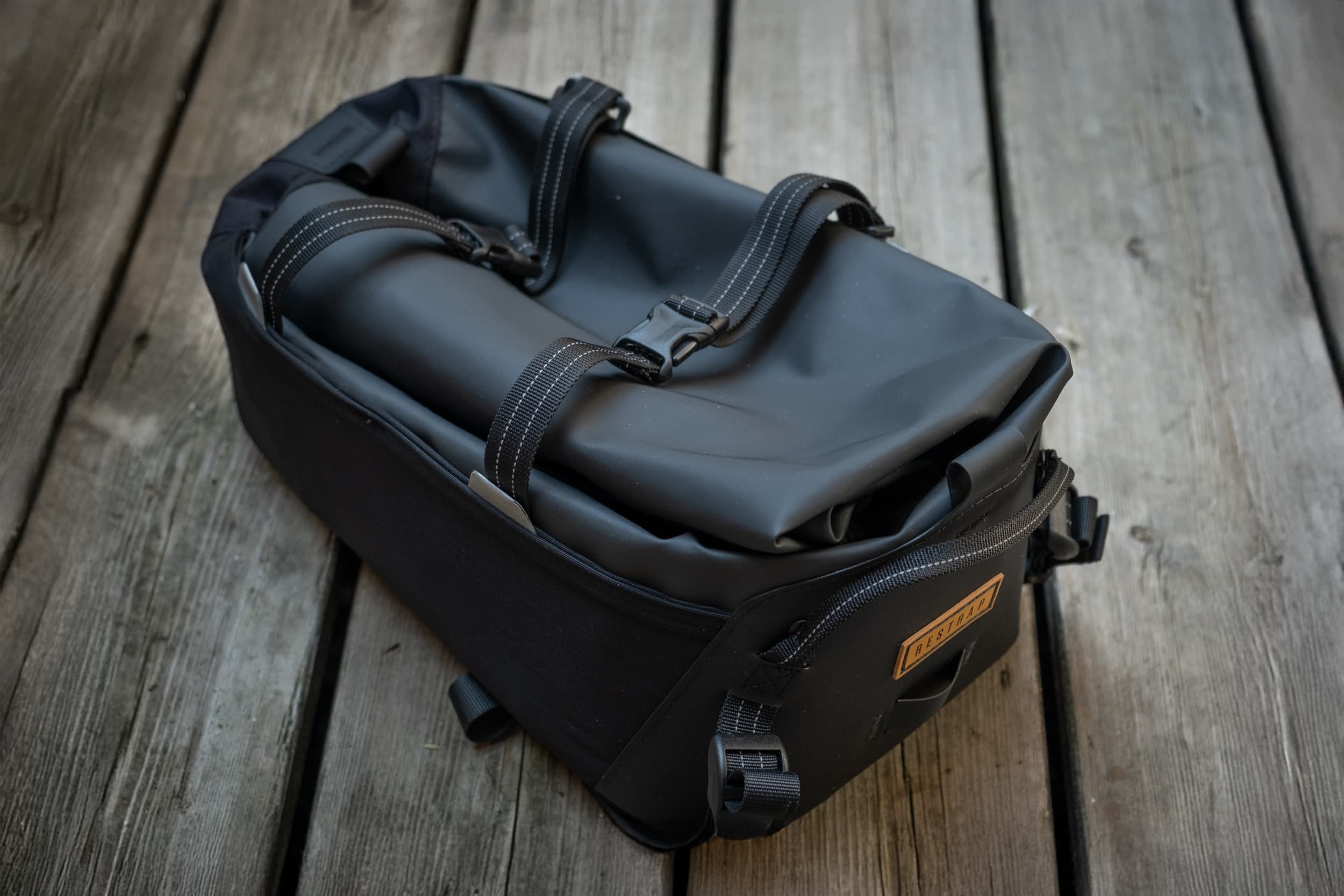 The Switch Top Bag, rolltop closed, resting on the same wood deck.