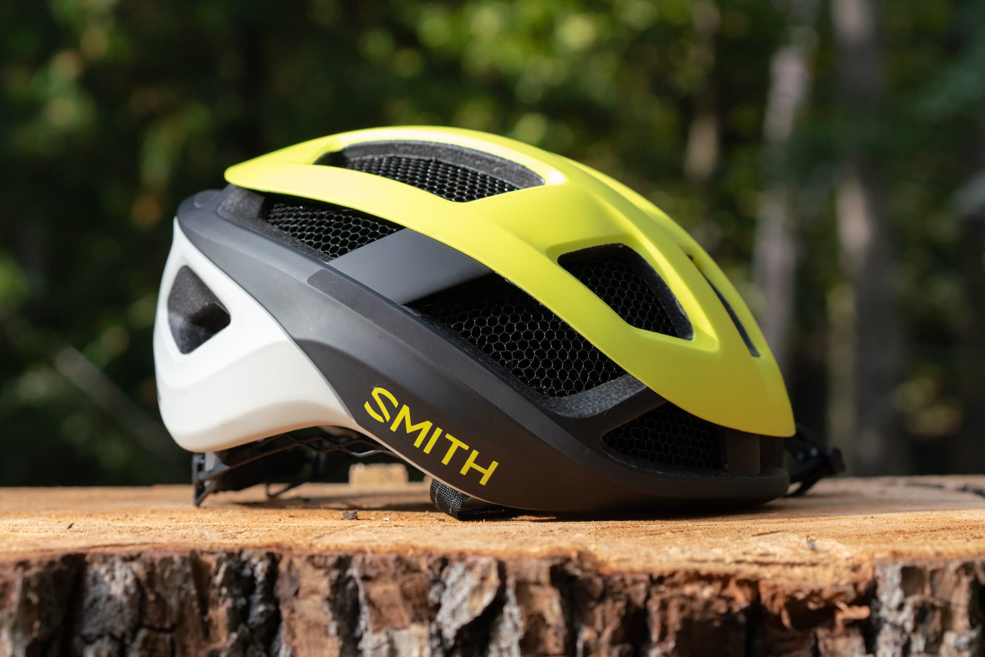 Side profile of the Smith Trace MIPS in chartreuse, sitting on a stump in the forest.