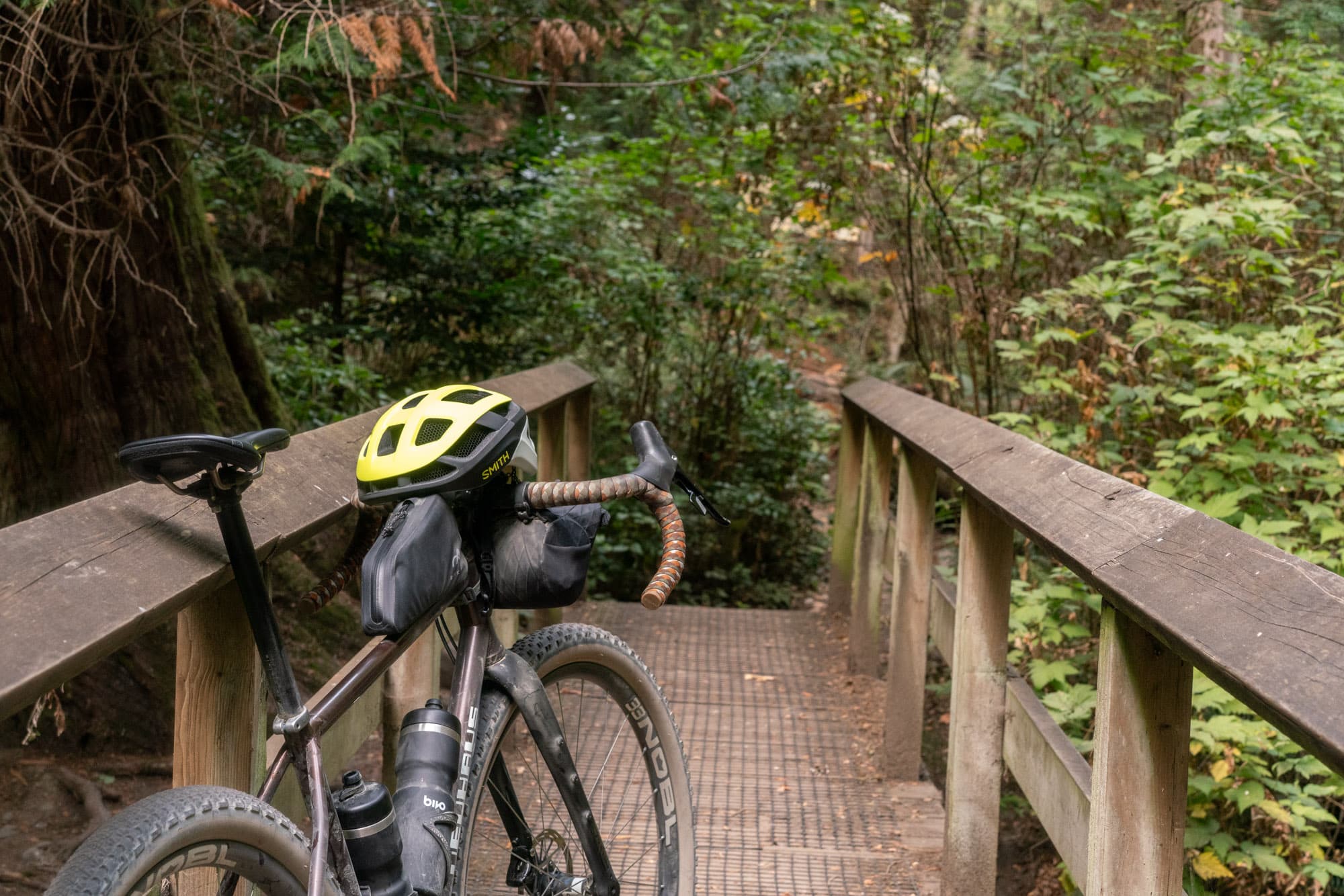The Smith Trace resting on Barry's gravel bike, parked on a wooden footbridge in the forest.