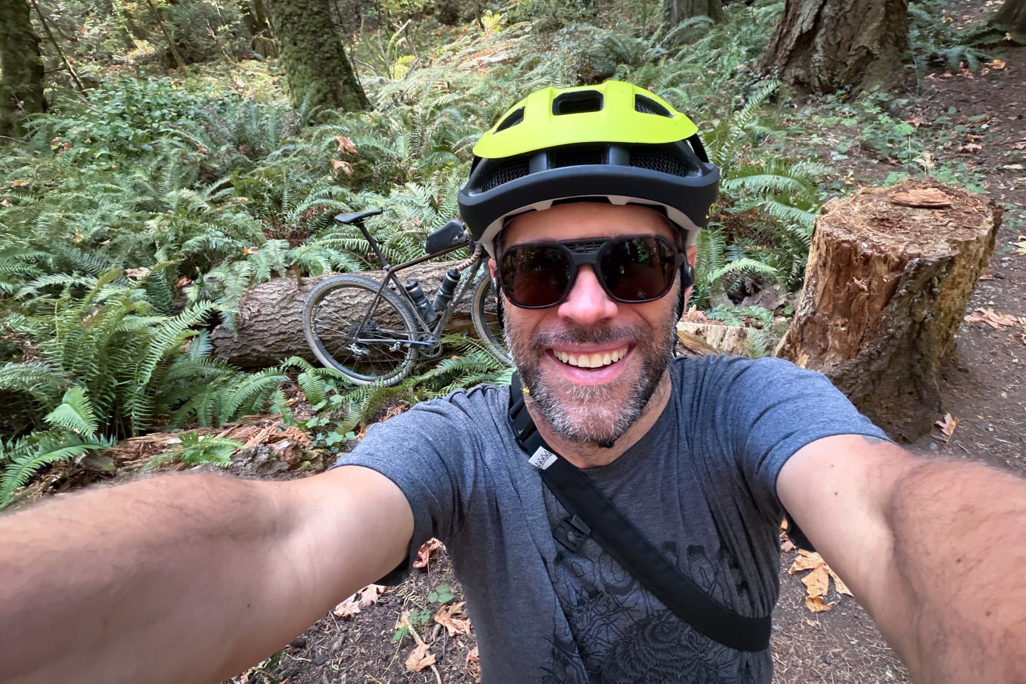 Barry grinning in the Smith Trace on a forest trail, bike behind him.
