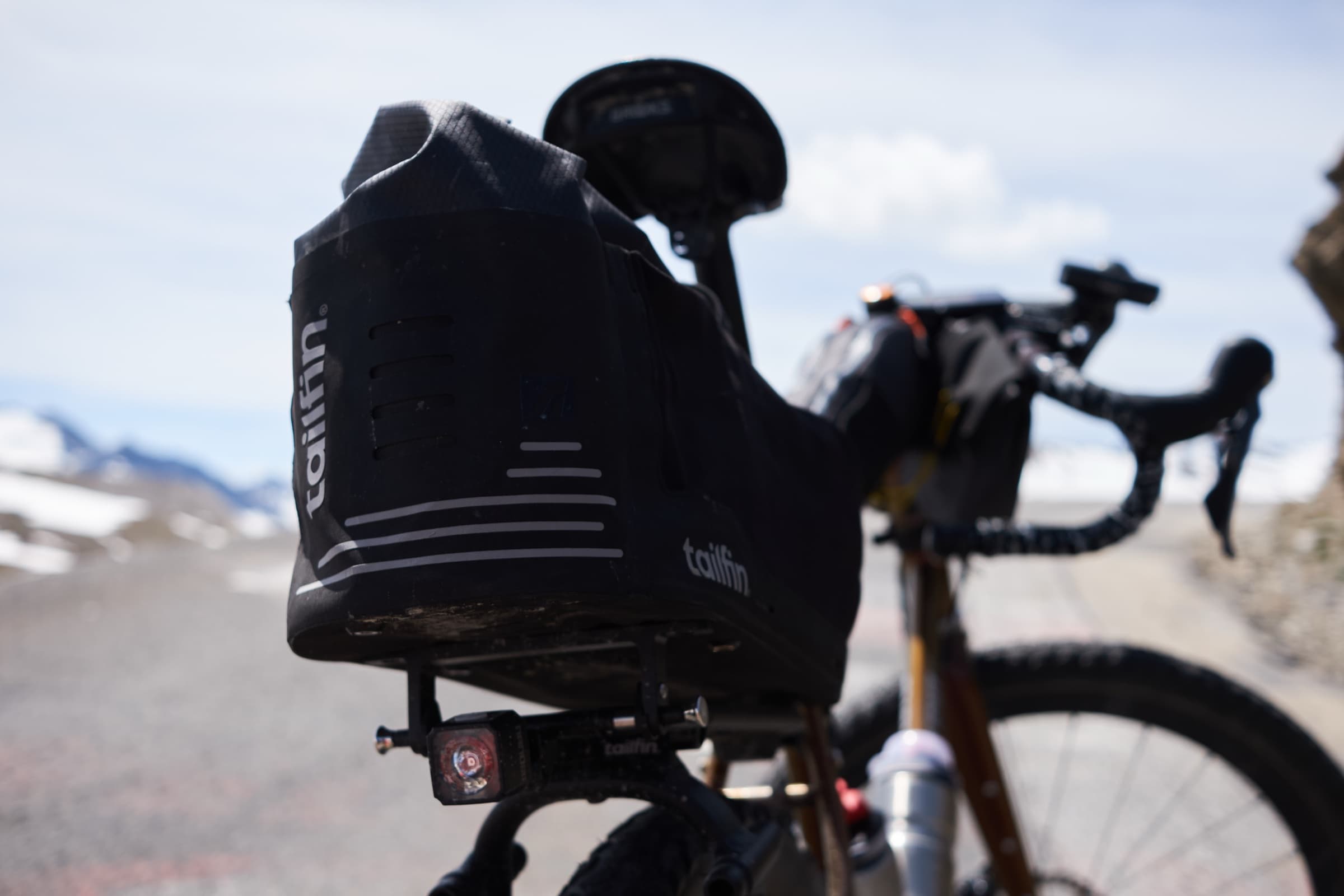 Side profile of the CargoPack mounted on the rack along a mountain pass road.