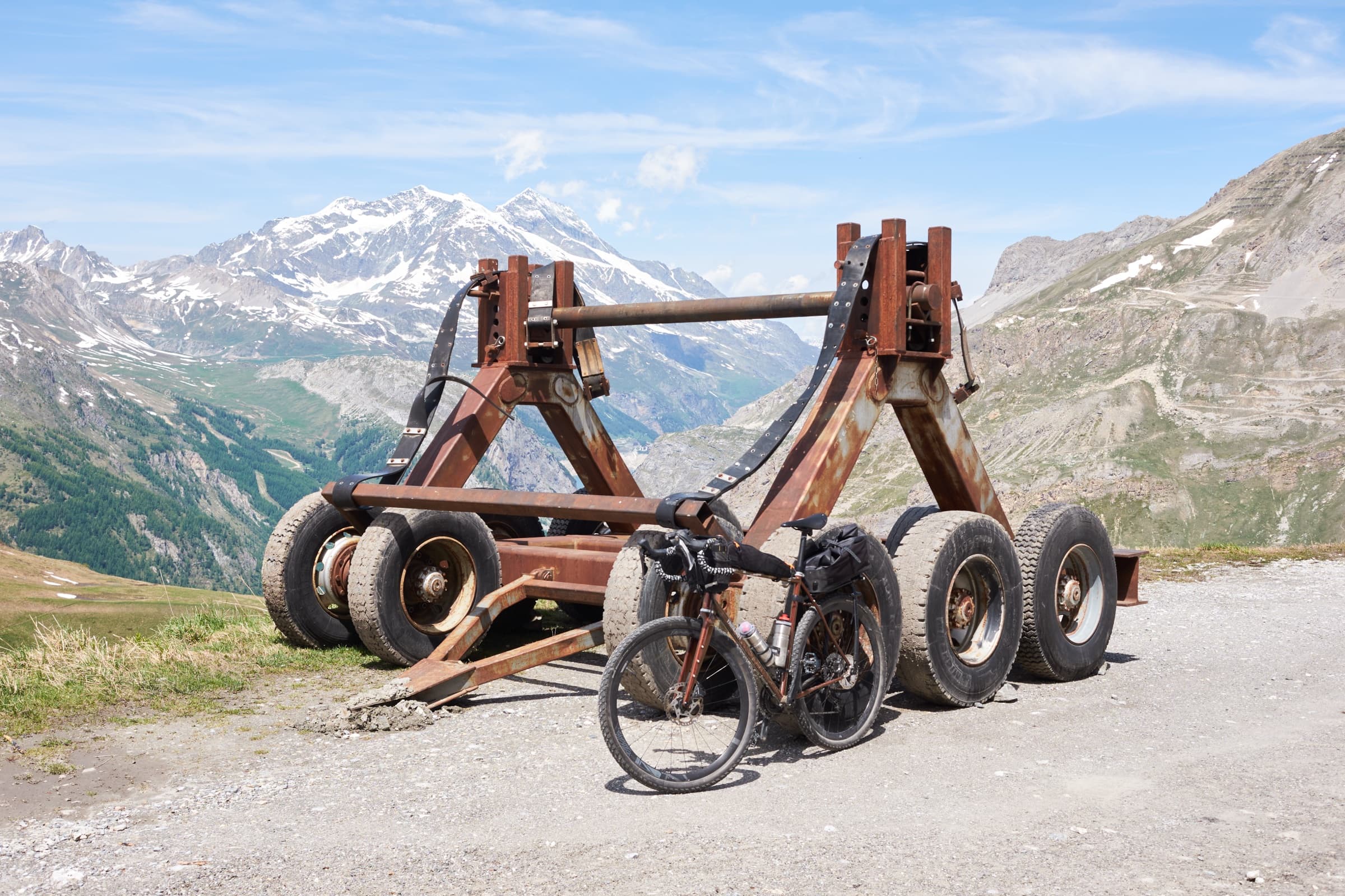 The bike parked beside rusting mountain machinery on an alpine pass.