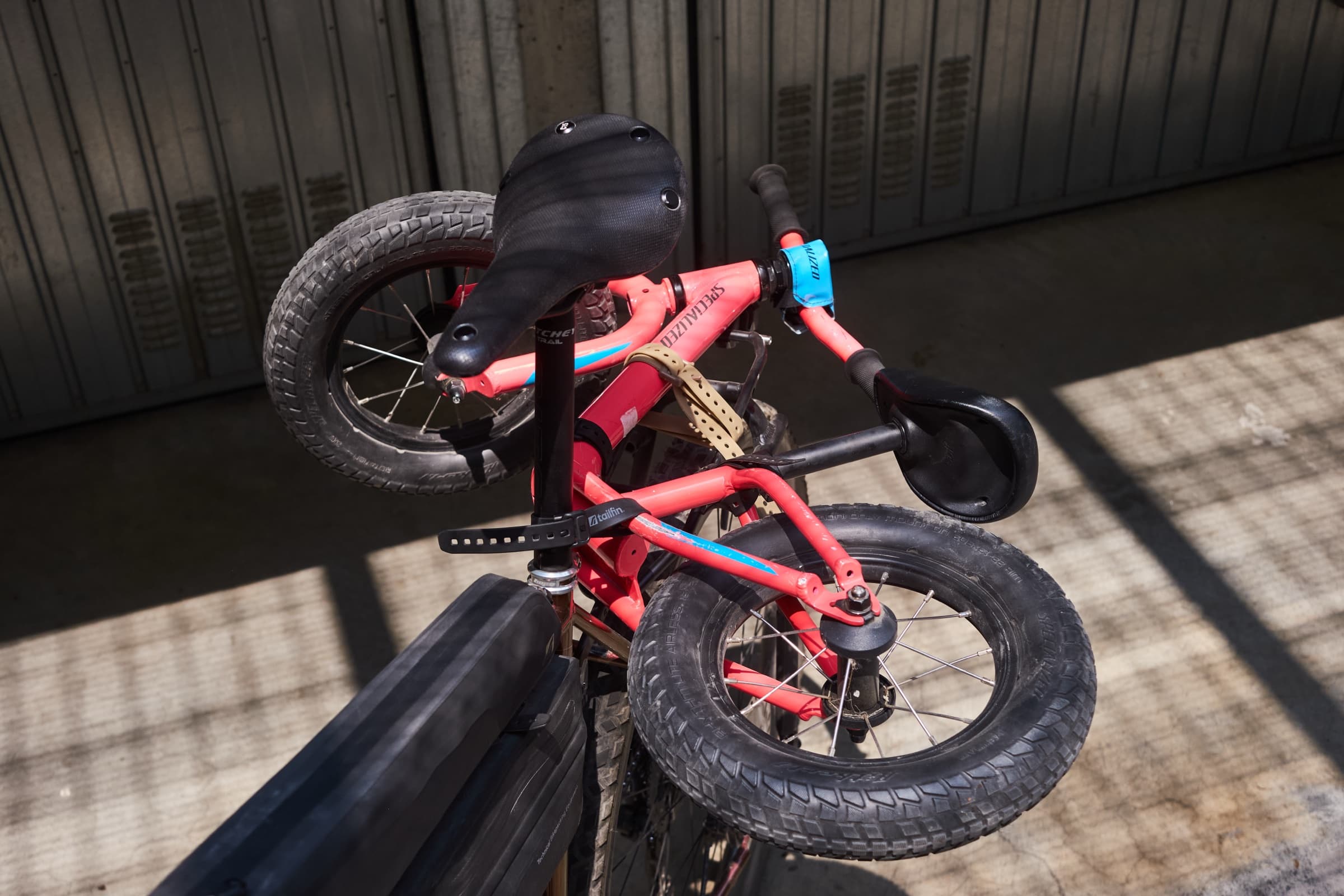 A child's balance bike strapped to the top of the rack.