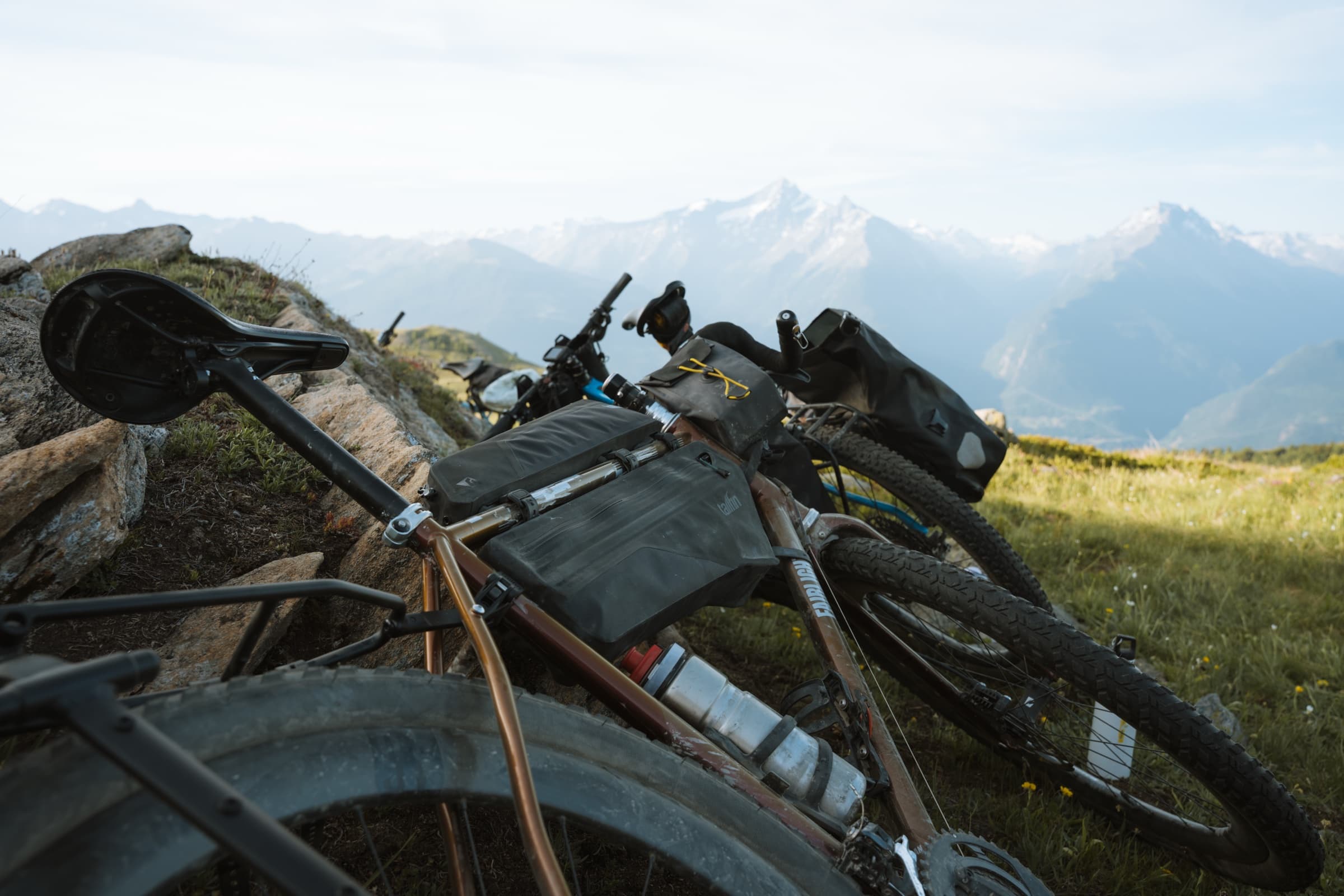 The bikes resting on a rocky outcrop above a mountain panorama.